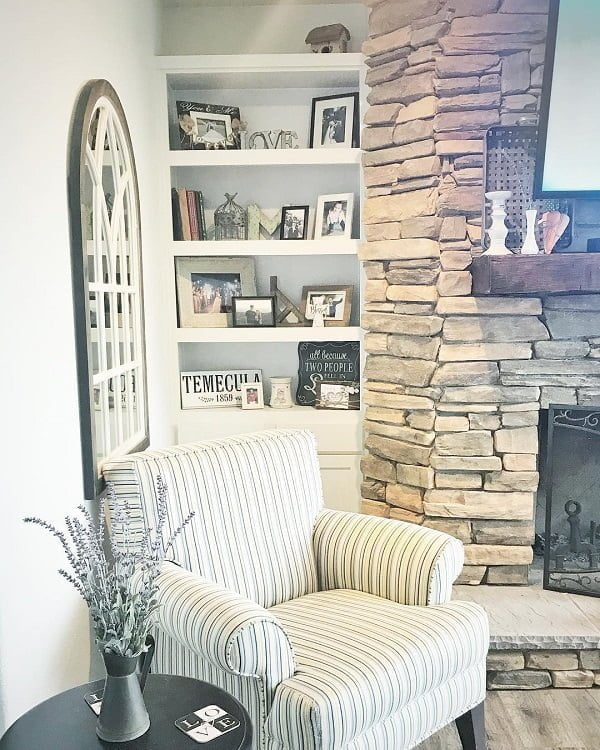 living room decor idea with internal window overlooking the impactful stone fireplace. Love it!