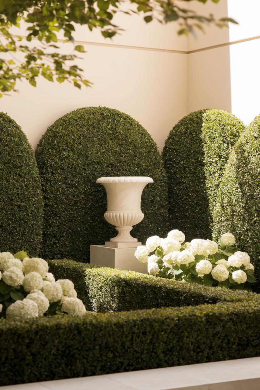 Boxwood hedges surrounding a classic urn with white blooms