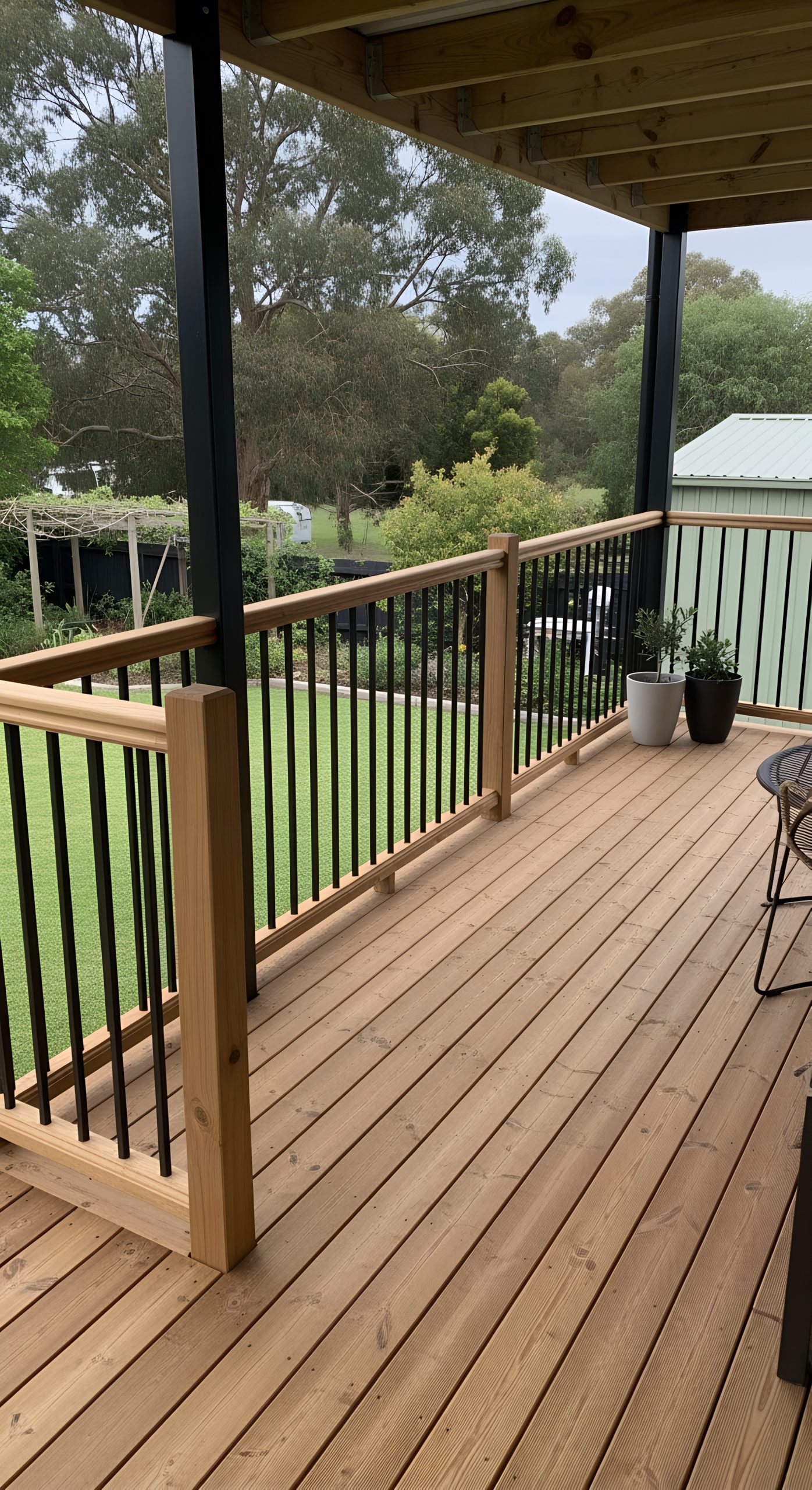 Wooden deck with sleek black railing and lush green backdrop