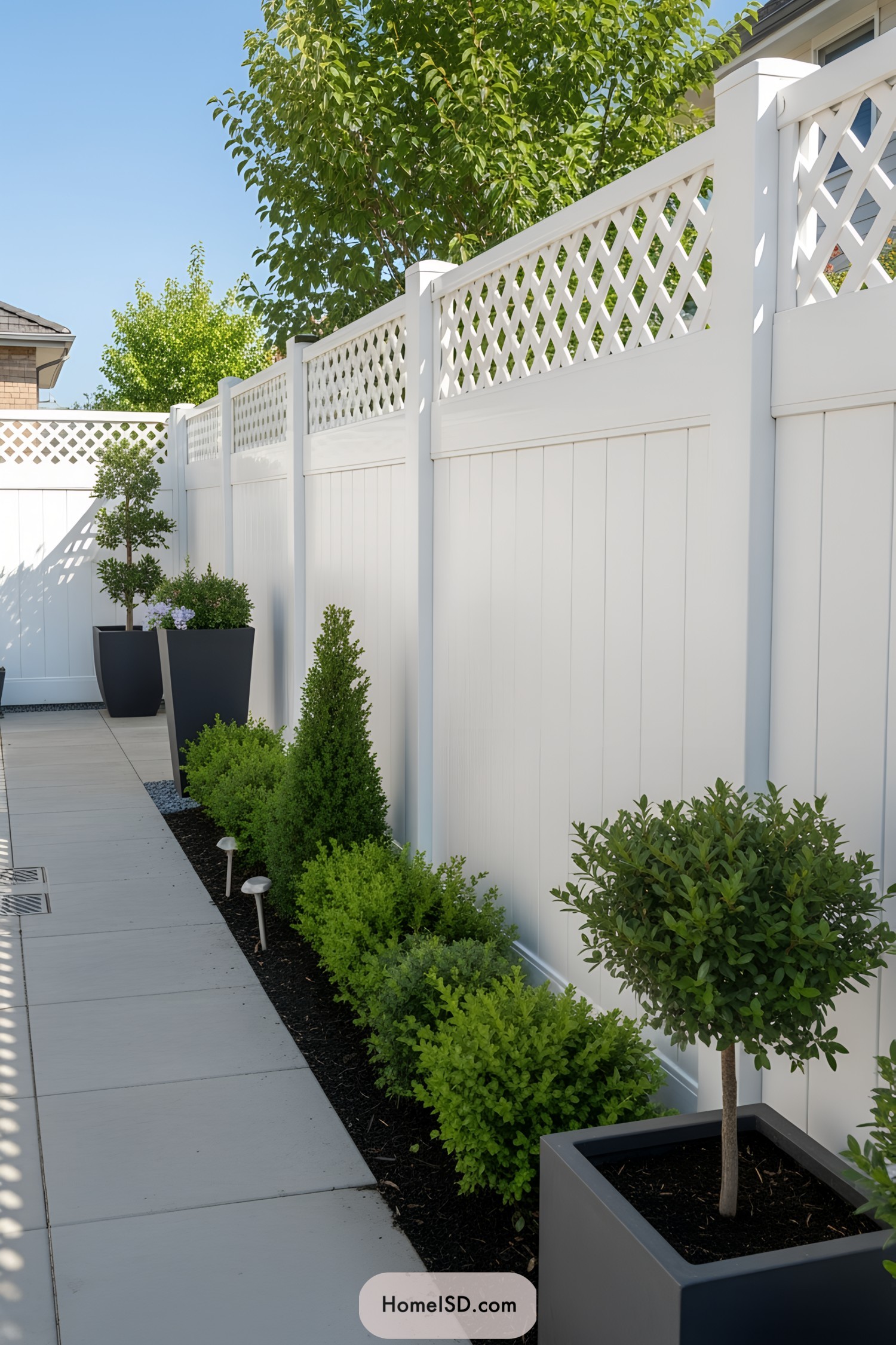 White privacy fence with lattice top and neatly trimmed greenery