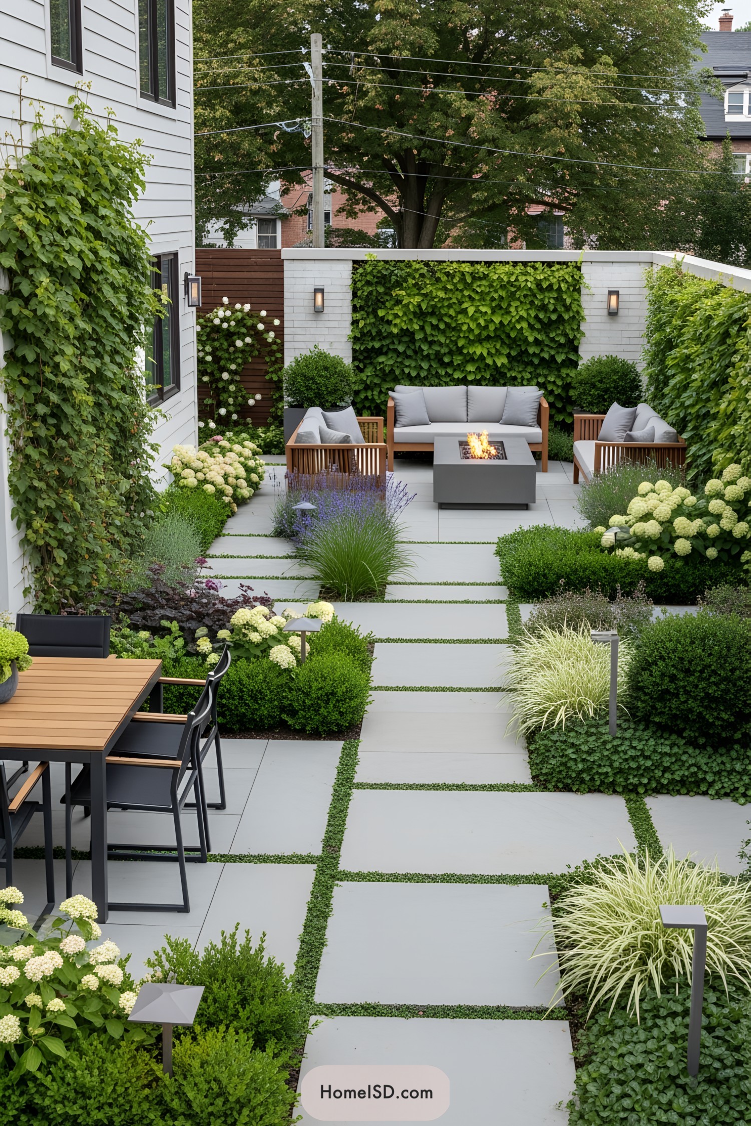 Elegant side yard with lush greenery, a cozy seating area, and a fire pit