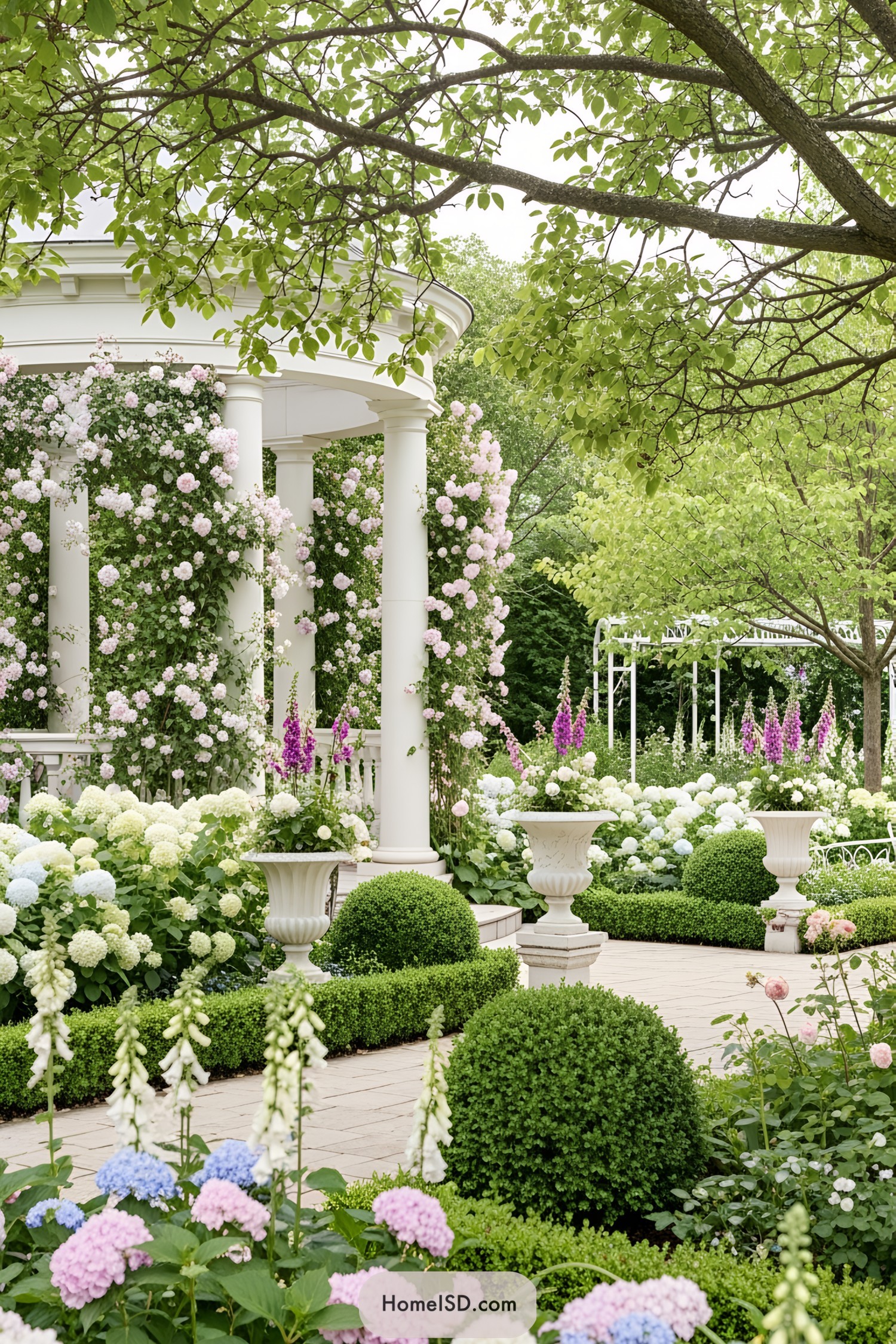 Coquette garden with a romantic and delicate aesthetic, filled with pastel-toned flowers including hydrangeas, roses, and foxgloves. A classical white pavilion with columns is enveloped by lush climbing florals and greenery. Manicured shrubs and tree canopies create soft shade, while elegant planters and subtle ornamental details enhance the graceful, serene atmosphere. The landscape evokes a dreamy and enchanting ambiance.