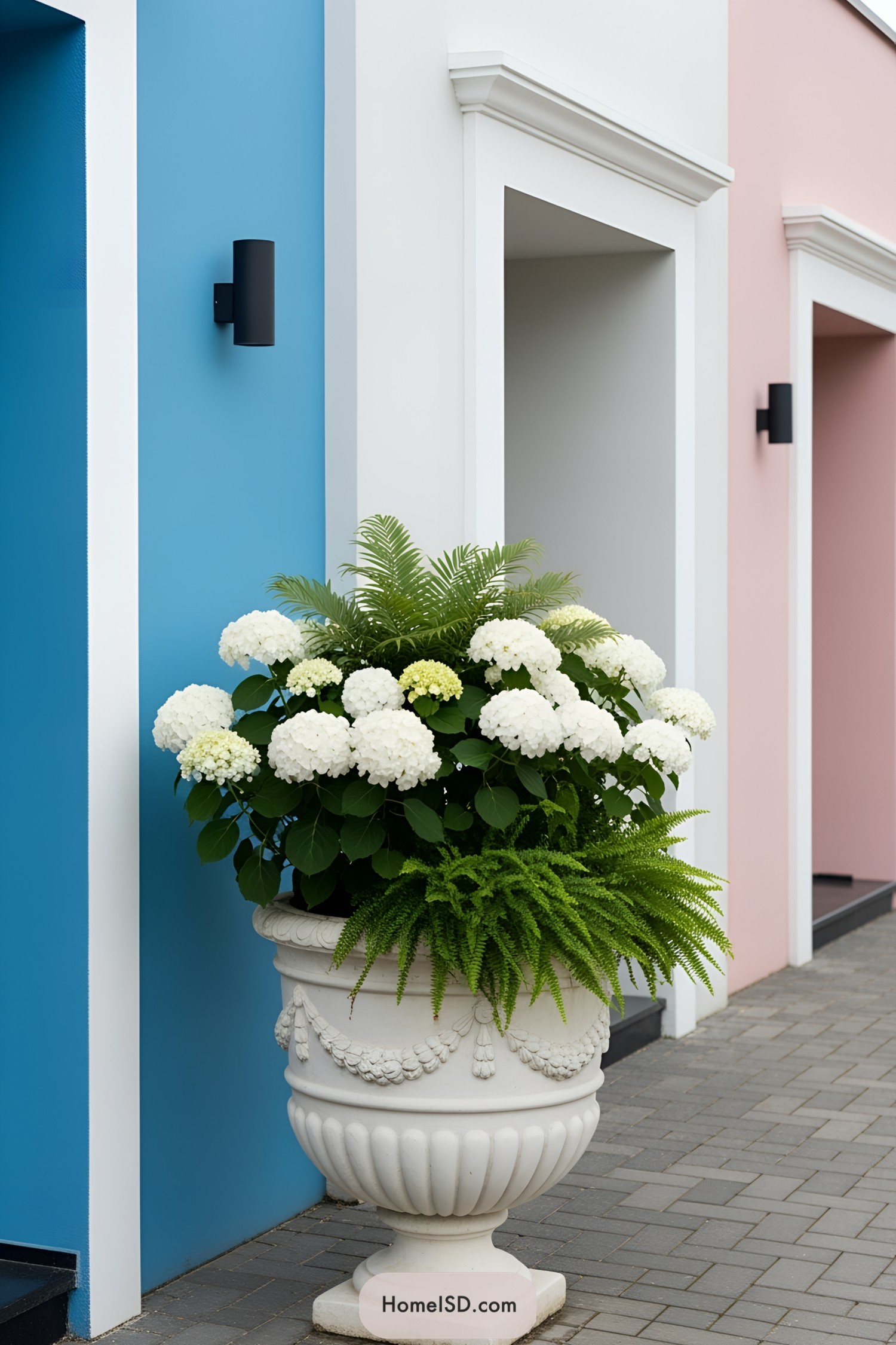 Large floral arrangement in a classic urn next to colorful building walls