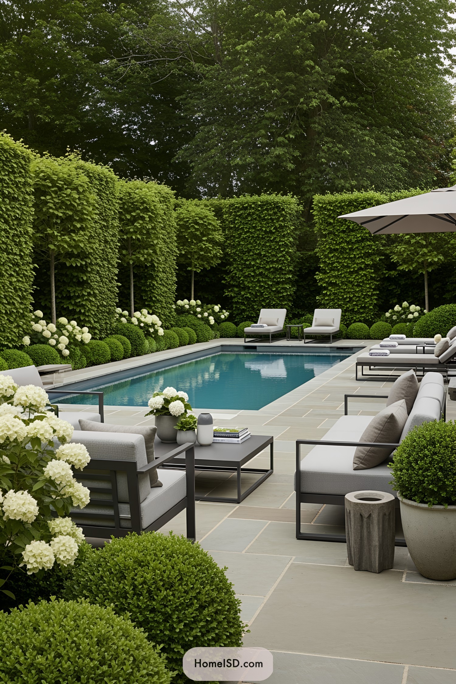 Luxurious pool surrounded by hedges and modern furniture