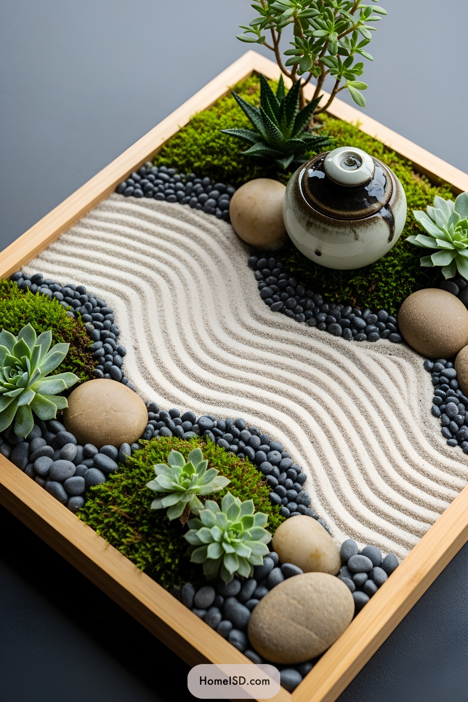 Miniature zen garden with sand, pebbles, and plants in a wooden frame