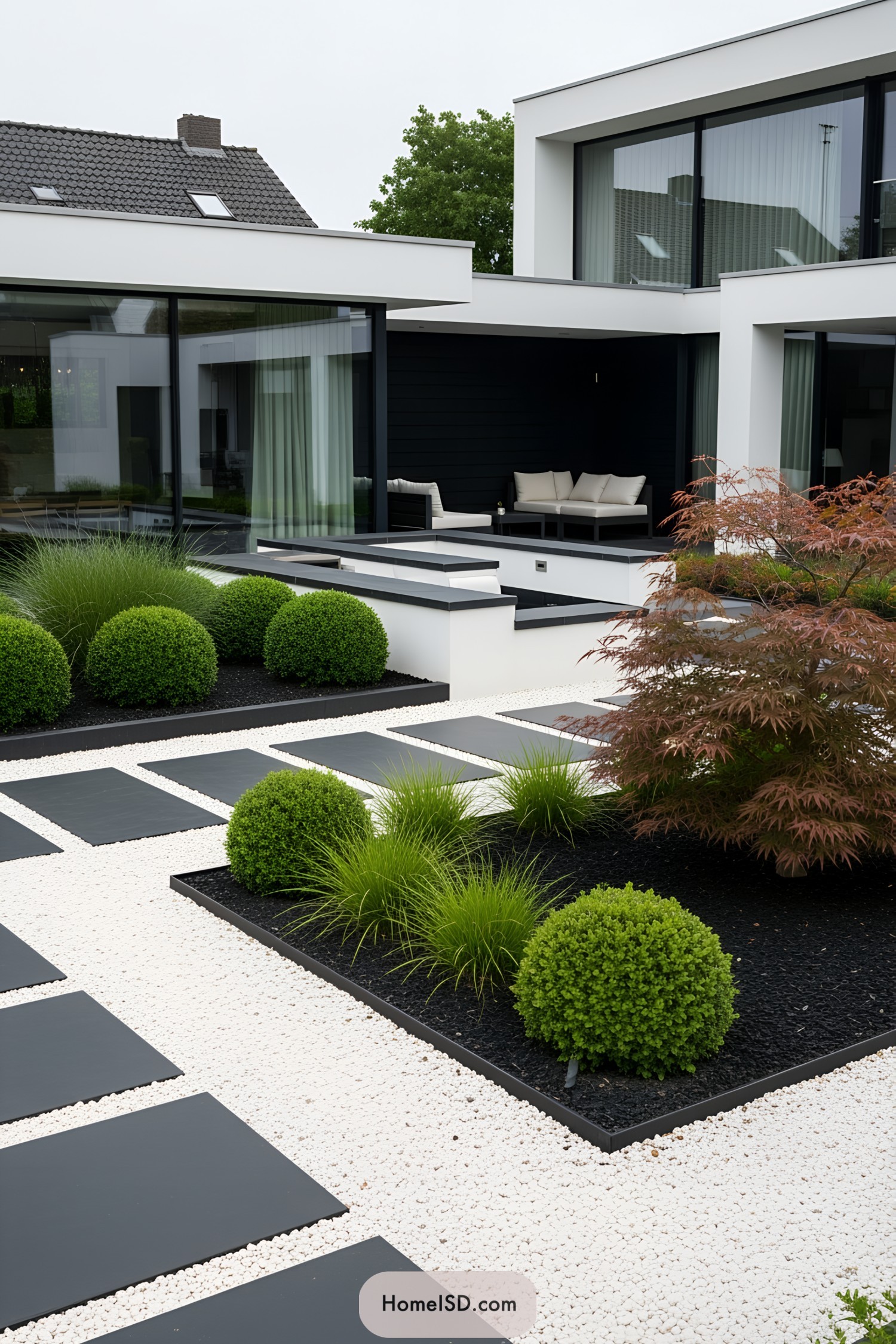 A modern, minimalist backyard with green shrubs and a stylish patio area