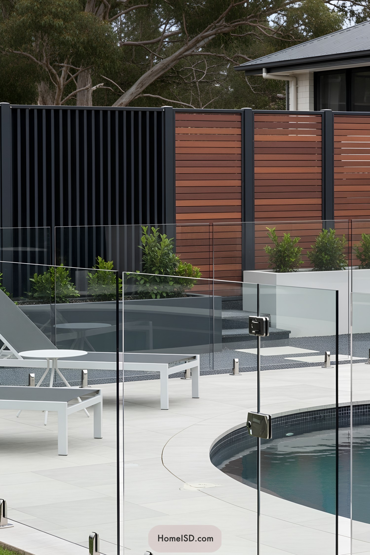 Glass fence surrounding a modern pool area with lounge chairs
