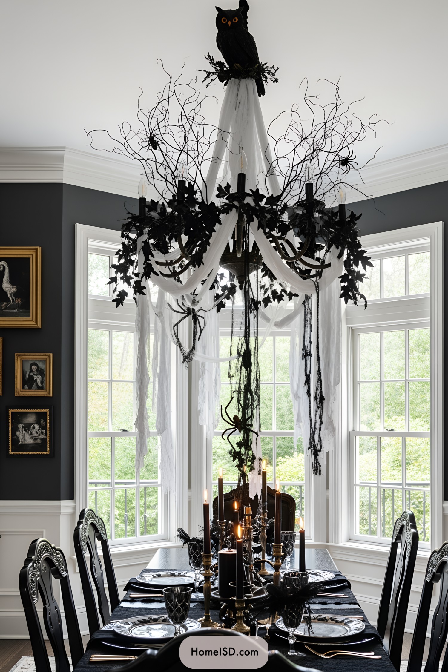 Halloween-themed dining room with an owl perched on a chandelier adorned with black foliage