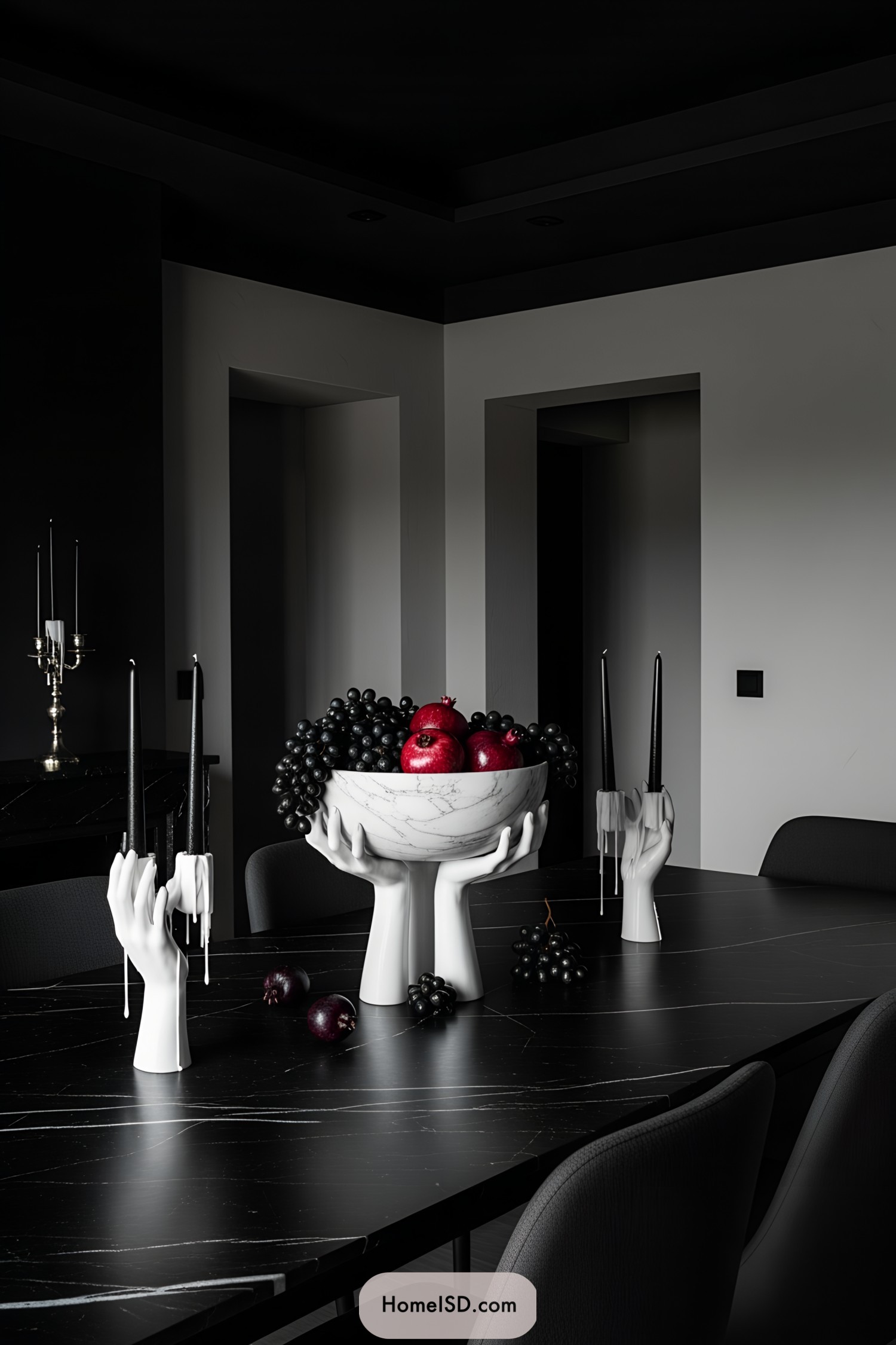 Dark table with white candleholders and a fruit bowl centerpiece