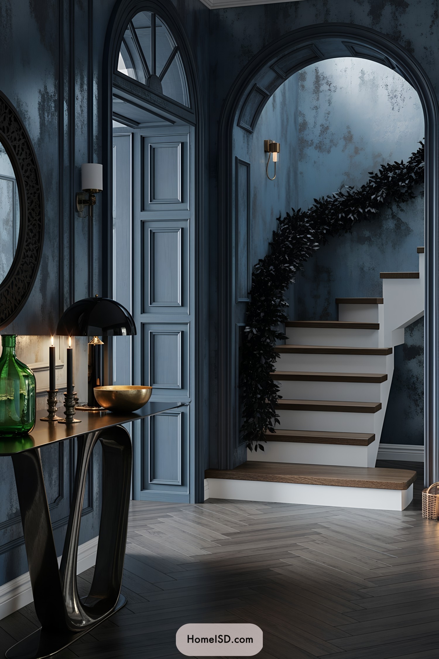 Entryway with a dramatic, moody aesthetic and modern-classic interior style, dominated by deep blue and charcoal tones. Textured, dark metallic wall with distressed finish creates an atmospheric backdrop. Ornate archways and paneled doors provide architectural interest. Floating wood staircase with a minimal white riser and dark wooden tread, decorated with dried black foliage garland for Halloween accents. Herringbone dark wood floor adds depth. Sleek, sculptural console table displays a green glass vase, tall black candle, and gold bowl under a black dome lamp. Subtle metallic accents and low, warm lighting enhance the luxe, haunted ambiance. No windows or visible greenery.