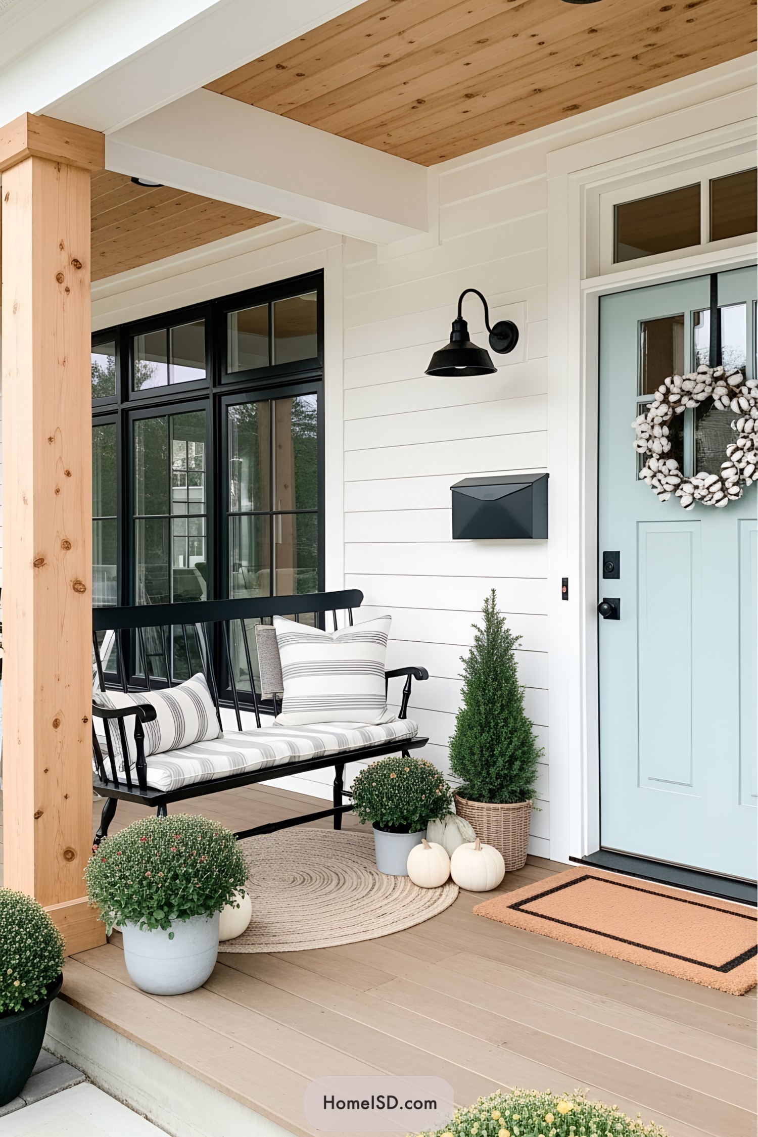 Front porch with a bench, striped pillows, and a wreath on the door
