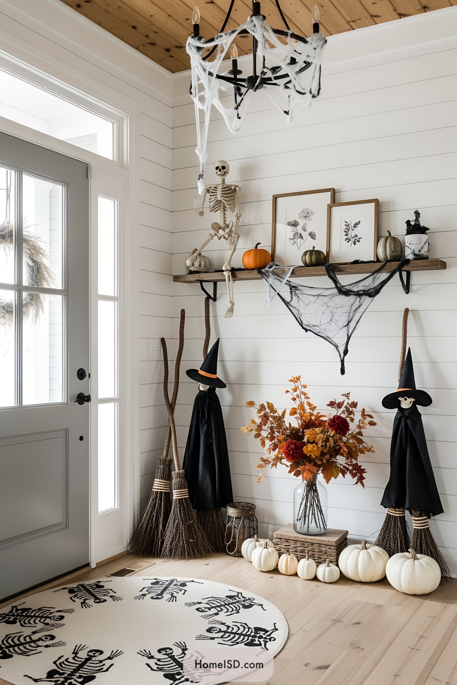 Elegant entryway with spooky Halloween decor, including broomsticks and witch hats