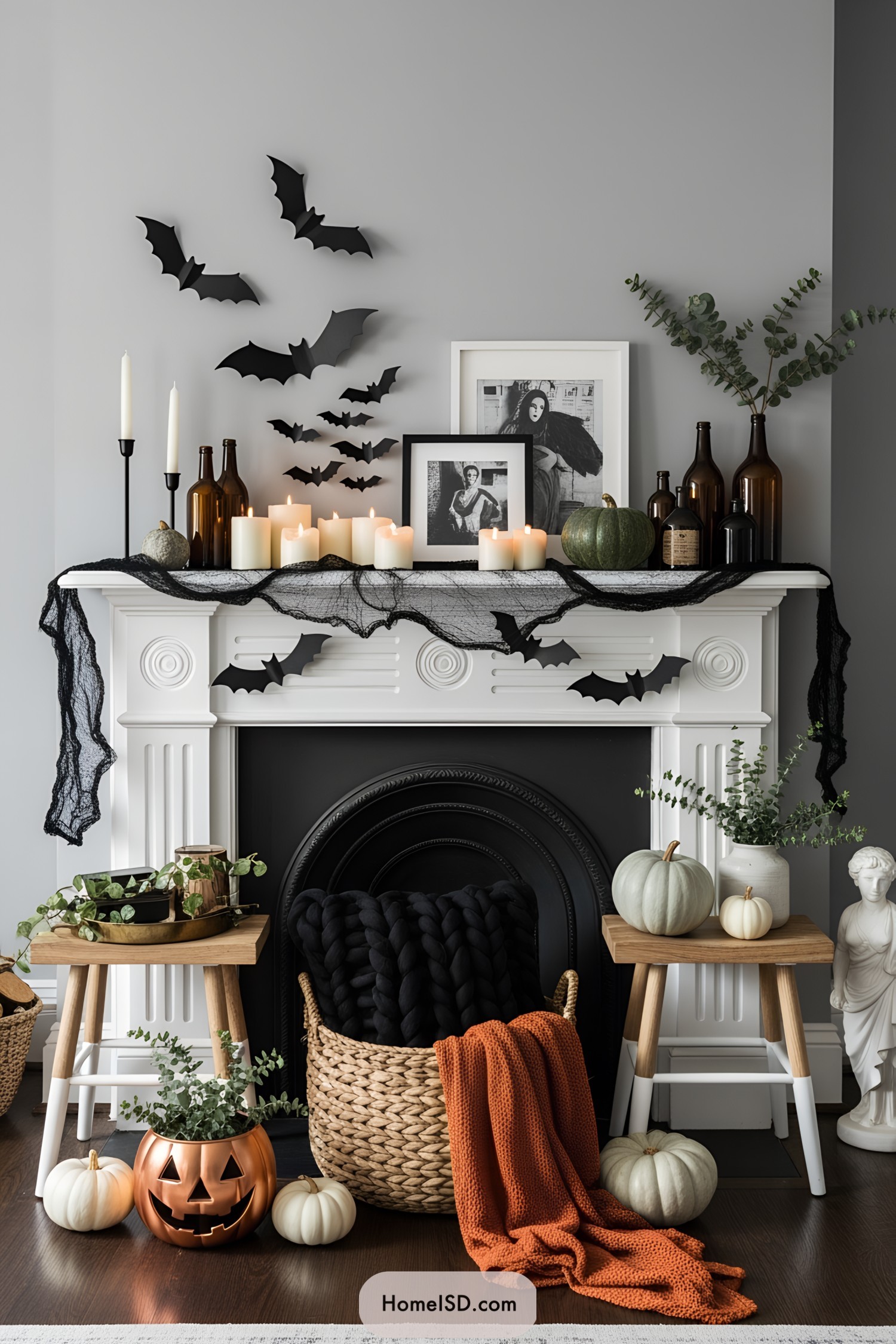 White mantel decorated with candles, bats, and pumpkins for Halloween