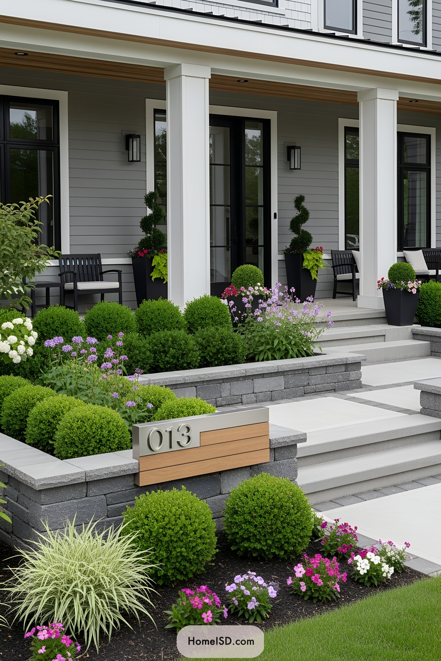 A modern house entrance with manicured shrubs and colorful flowers