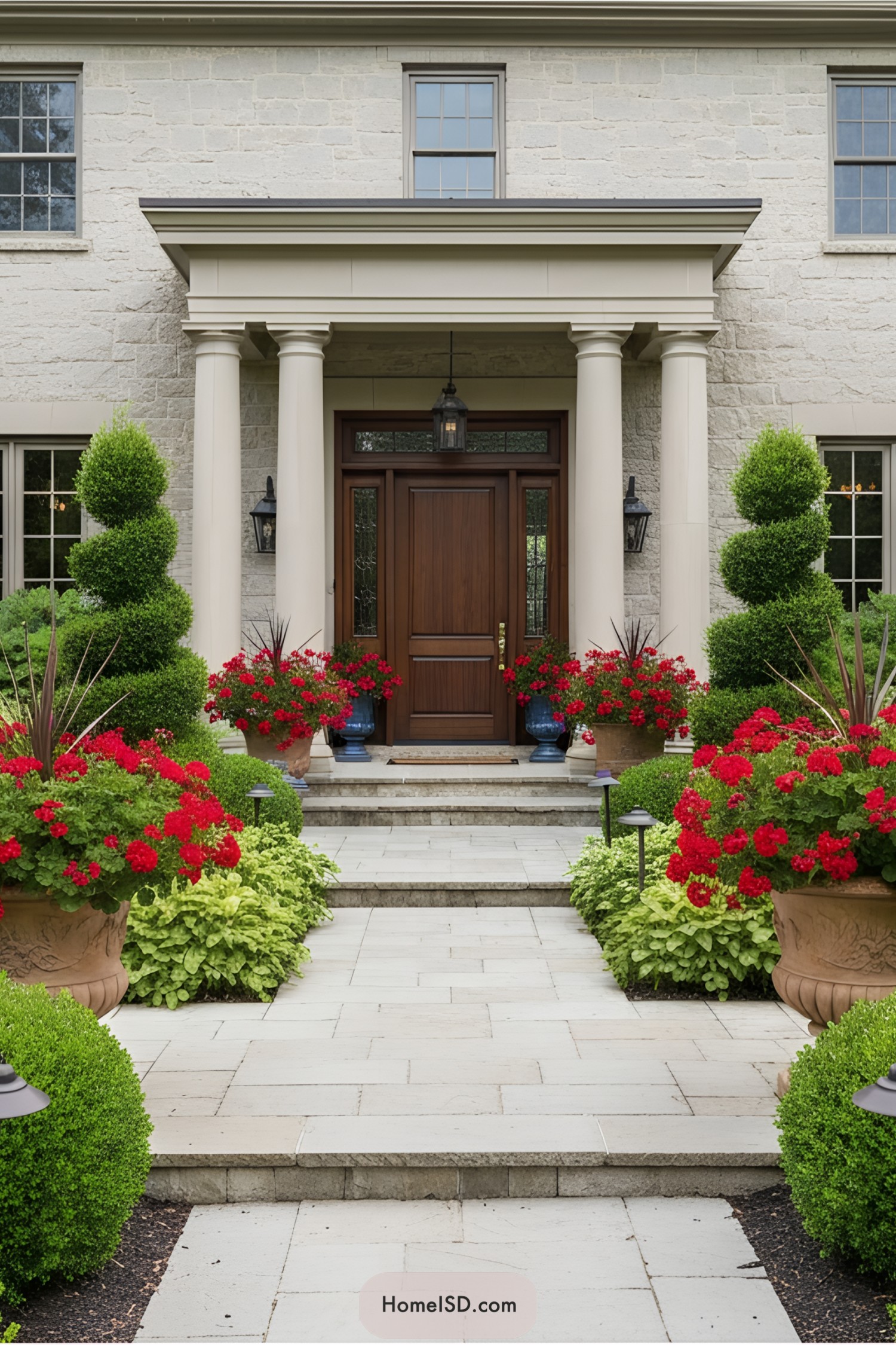 Front yard with colorful flowers and manicured hedges by a stately house entrance