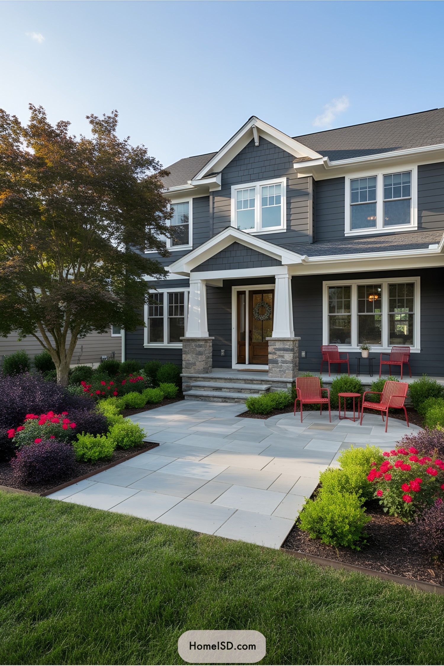 Front yard with pavers, colorful plants, and red chairs