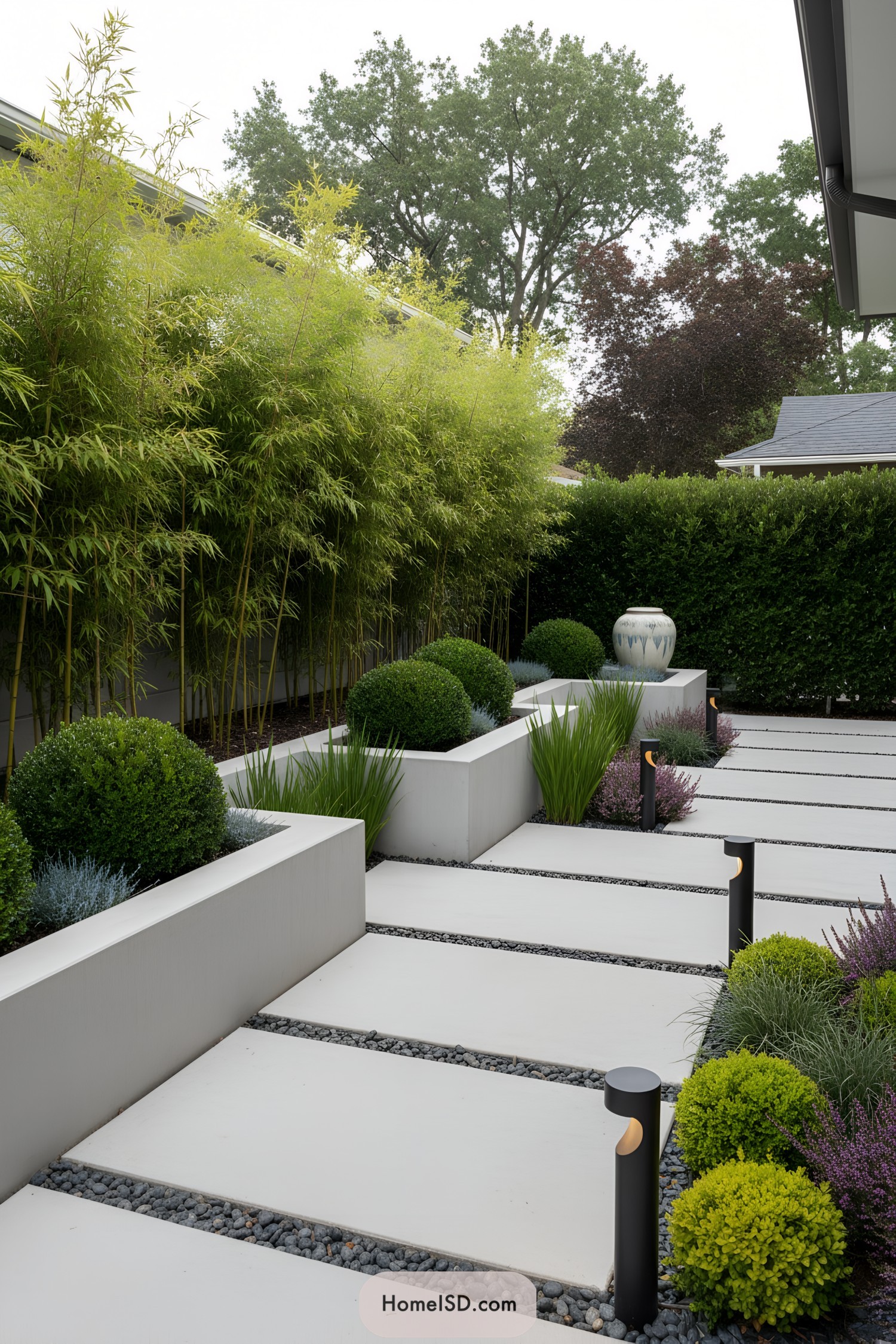Modern courtyard with white slab pavers, pebble joints, boxwood globes, bamboo hedge, and black bollard lights