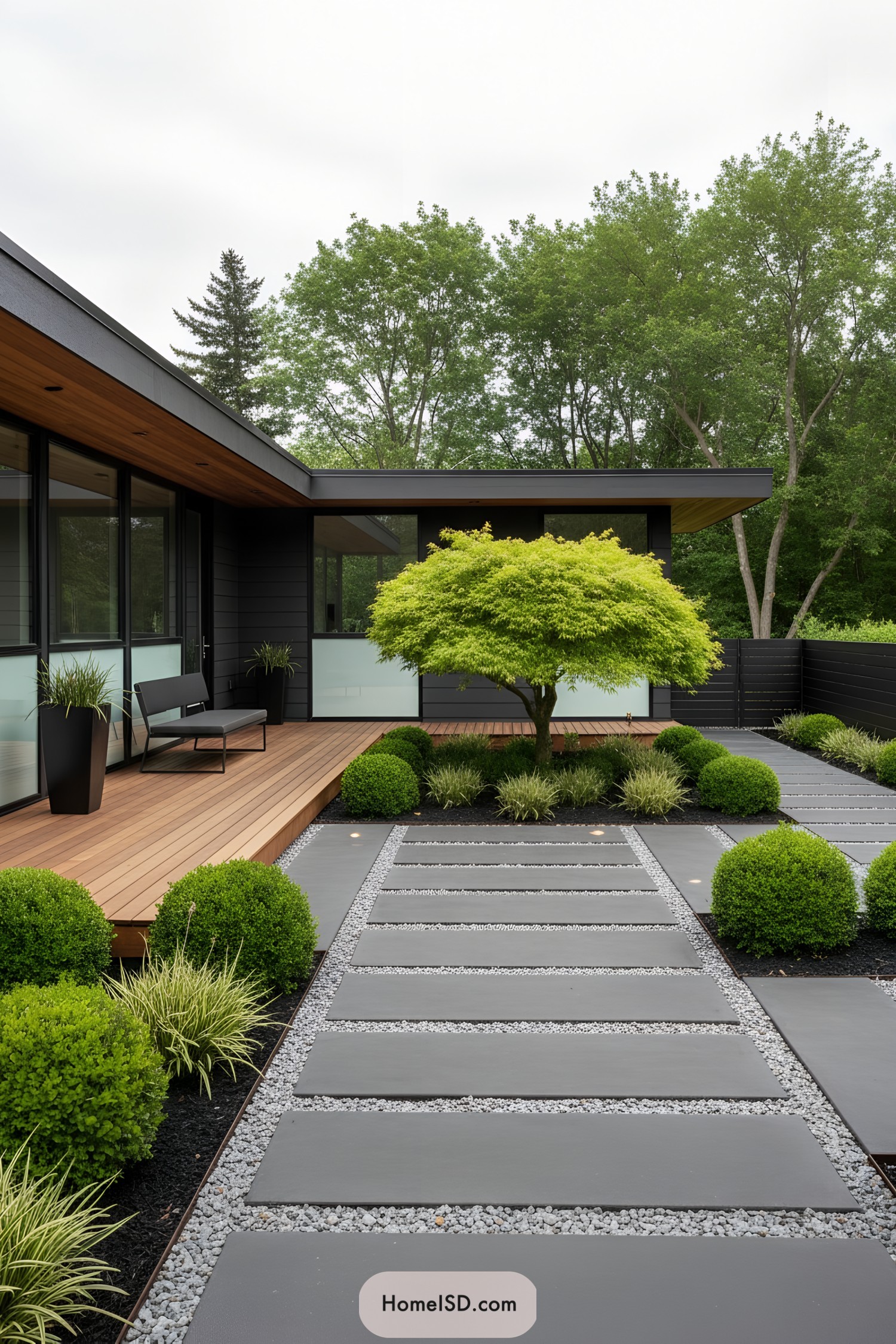 Modern yard with slate slab path, boxwood mounds, and a Japanese maple beside a cedar deck