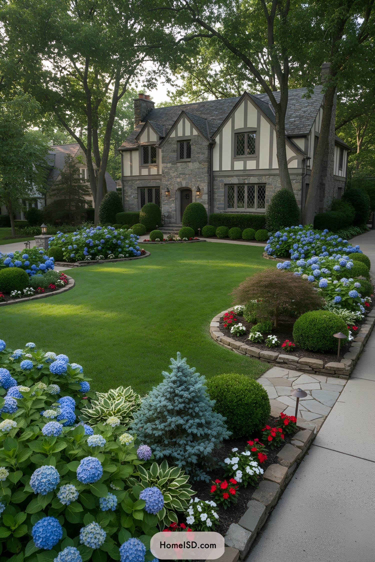 Curved beds with hydrangeas framing a manicured front lawn of a Tudor-style home