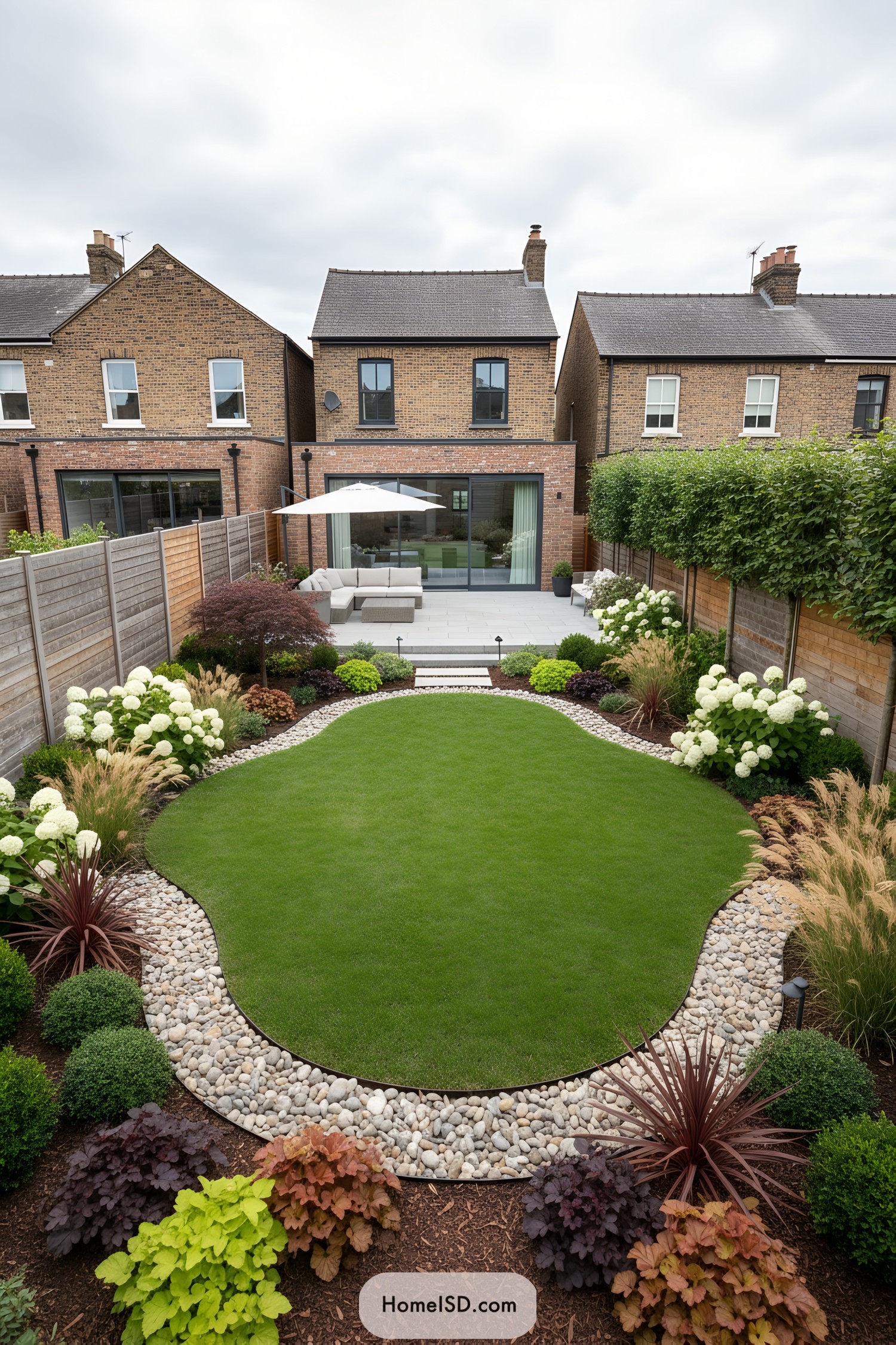Curved lawn edged by river rocks and mixed borders beside a modern patio
