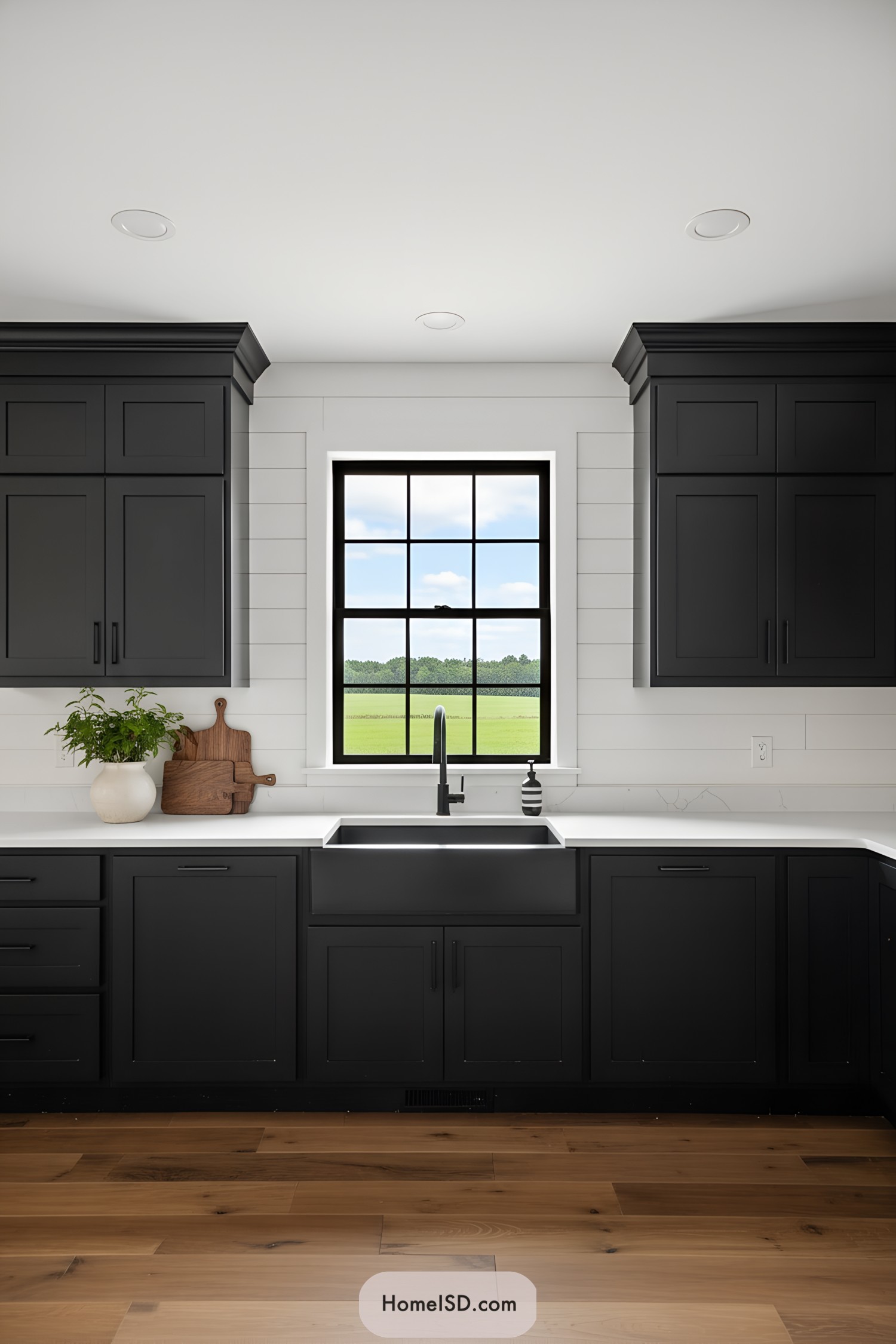 Black shaker cabinets with black hardware, white shiplap walls, and farmhouse sink