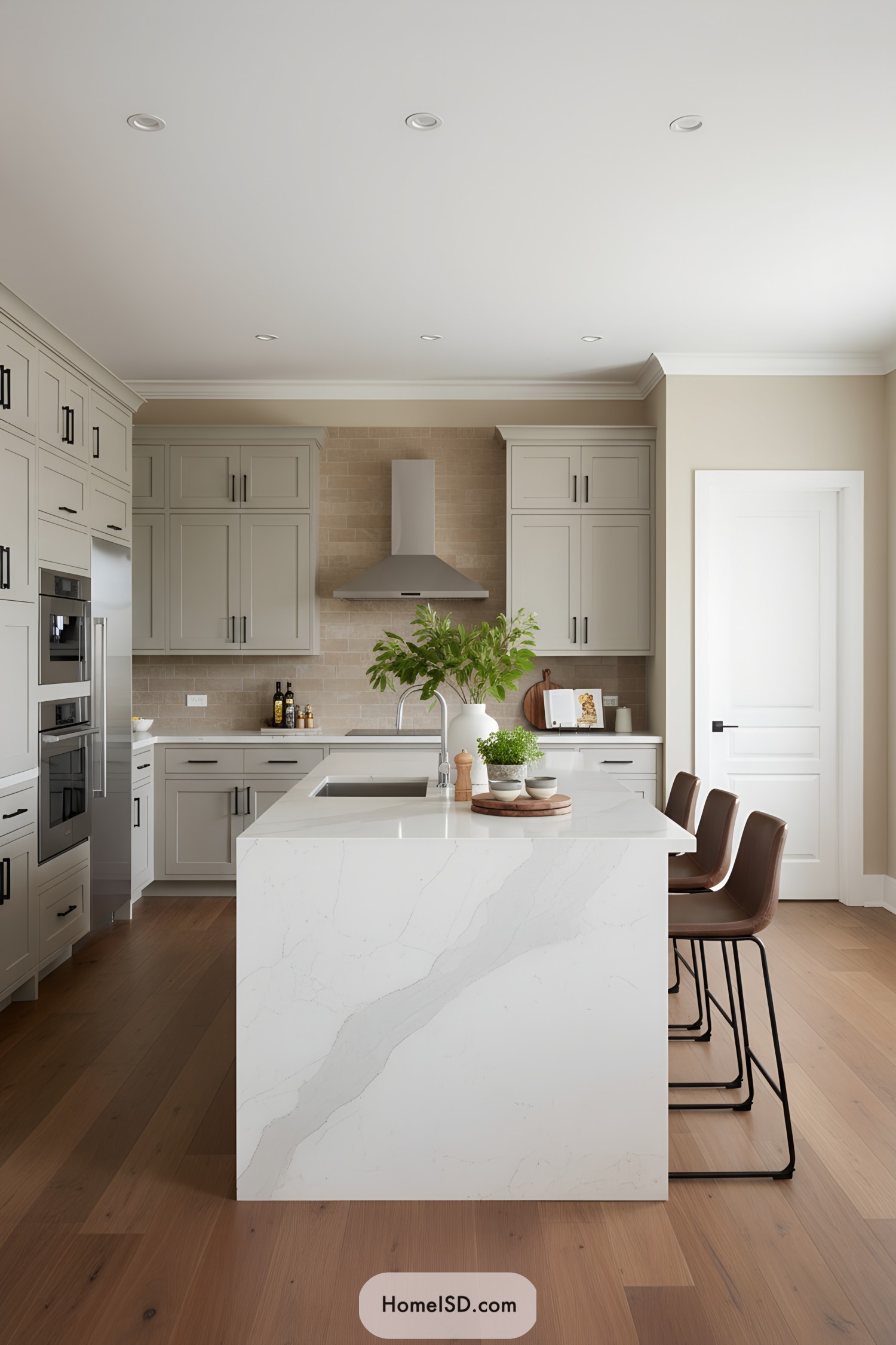Light gray shaker kitchen with quartz waterfall island, warm wood floors, and leather stools