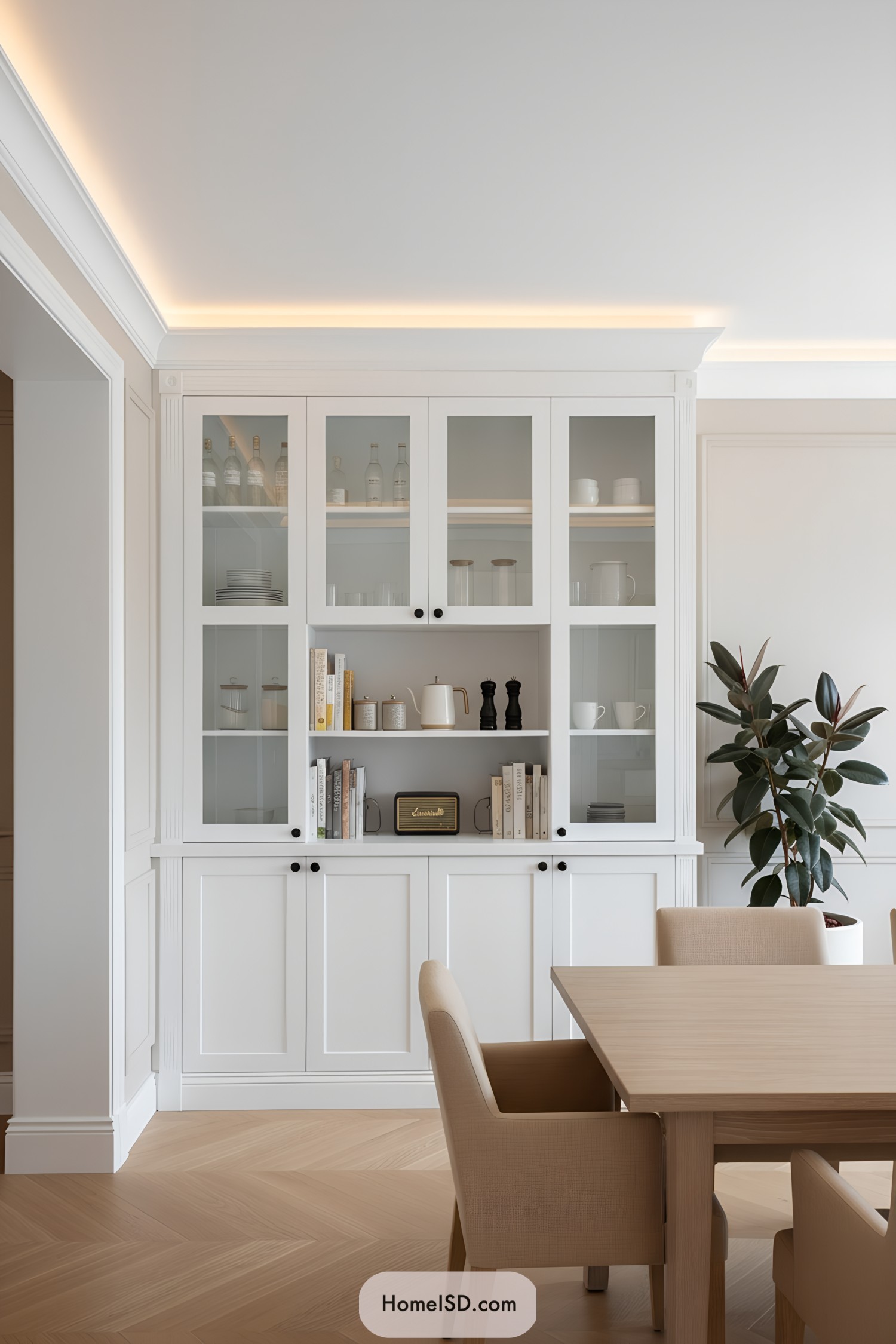White built-in china cabinet with glass doors and open shelf, styled with neutral serveware and books in a bright dining room