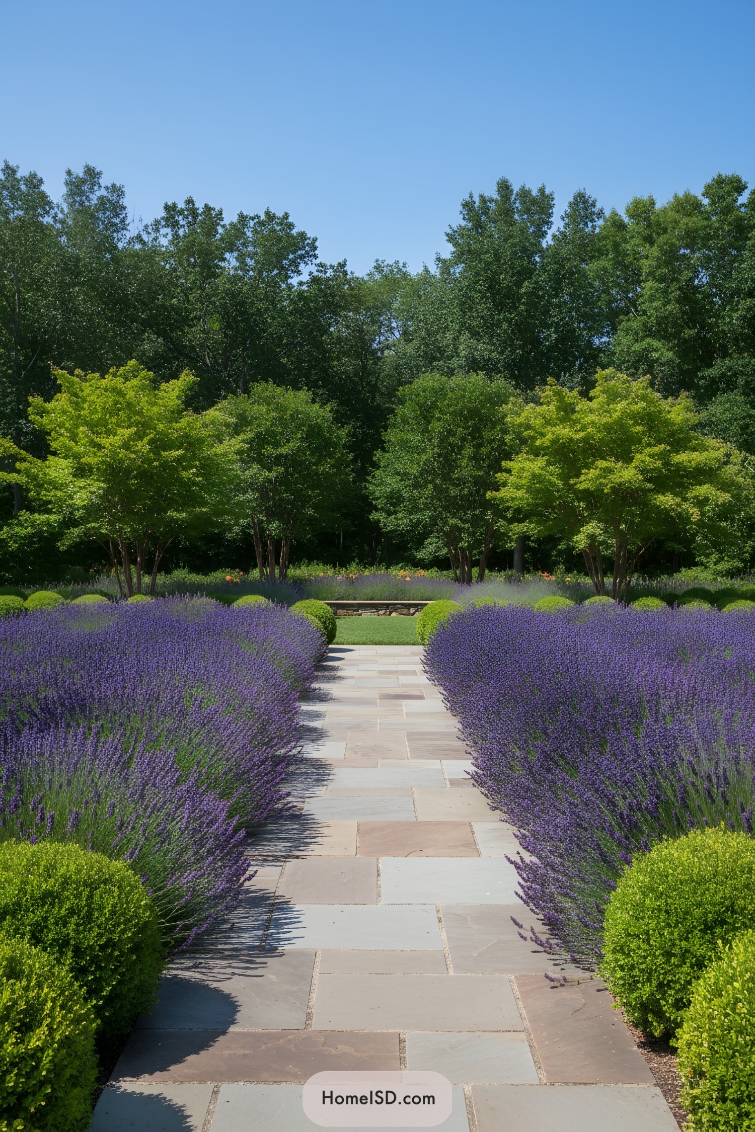 A stone path flanked by lush lavender bushes and trees in a serene garden