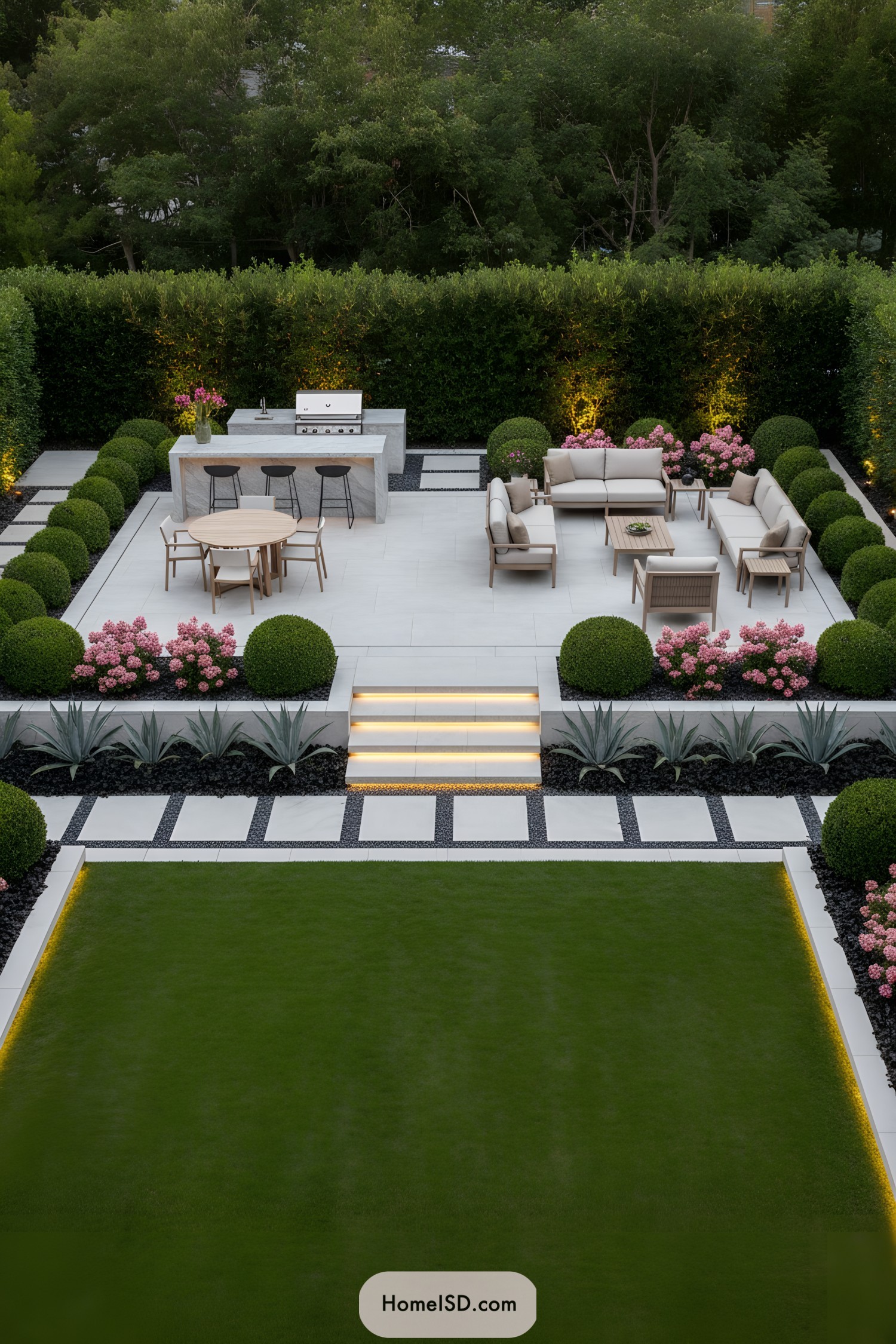 Modern patio with limestone pavers, trimmed hedges, and built-in grill framed by rounded boxwoods and pink blooms