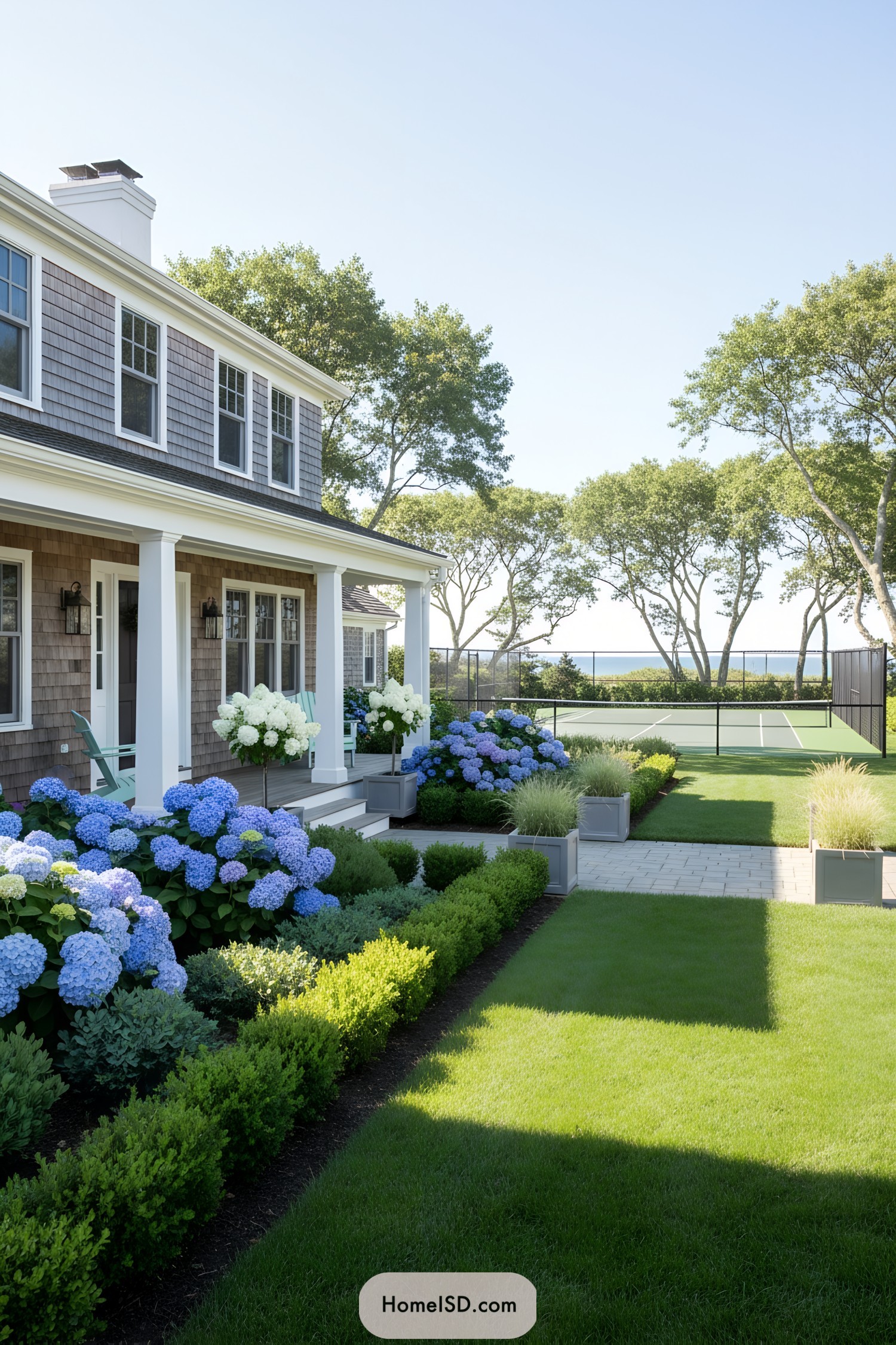 White-shingled coastal home with lush hydrangeas and tennis court