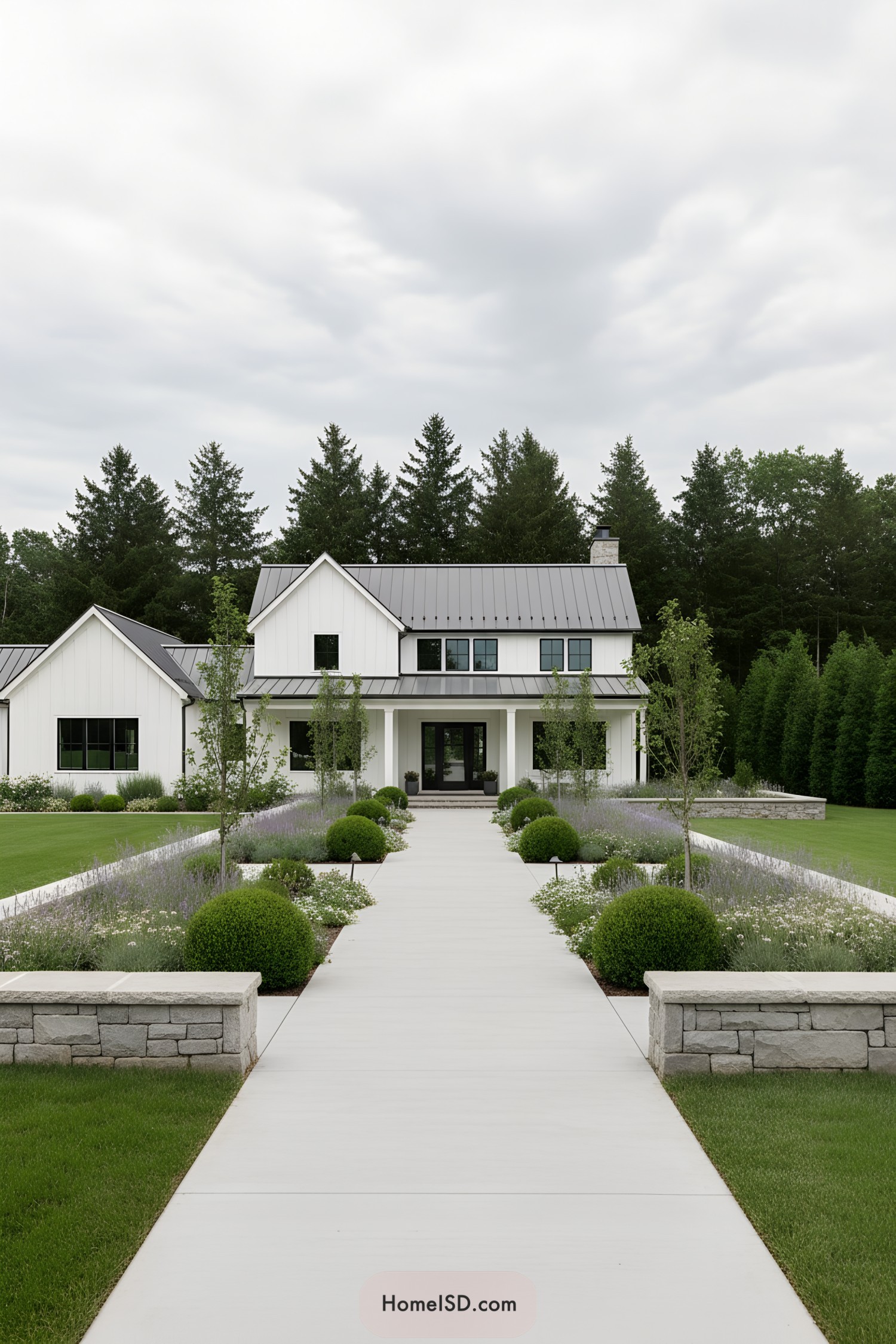 Modern white farmhouse with long, symmetrical garden walkway lined by boxwoods and soft flowering borders