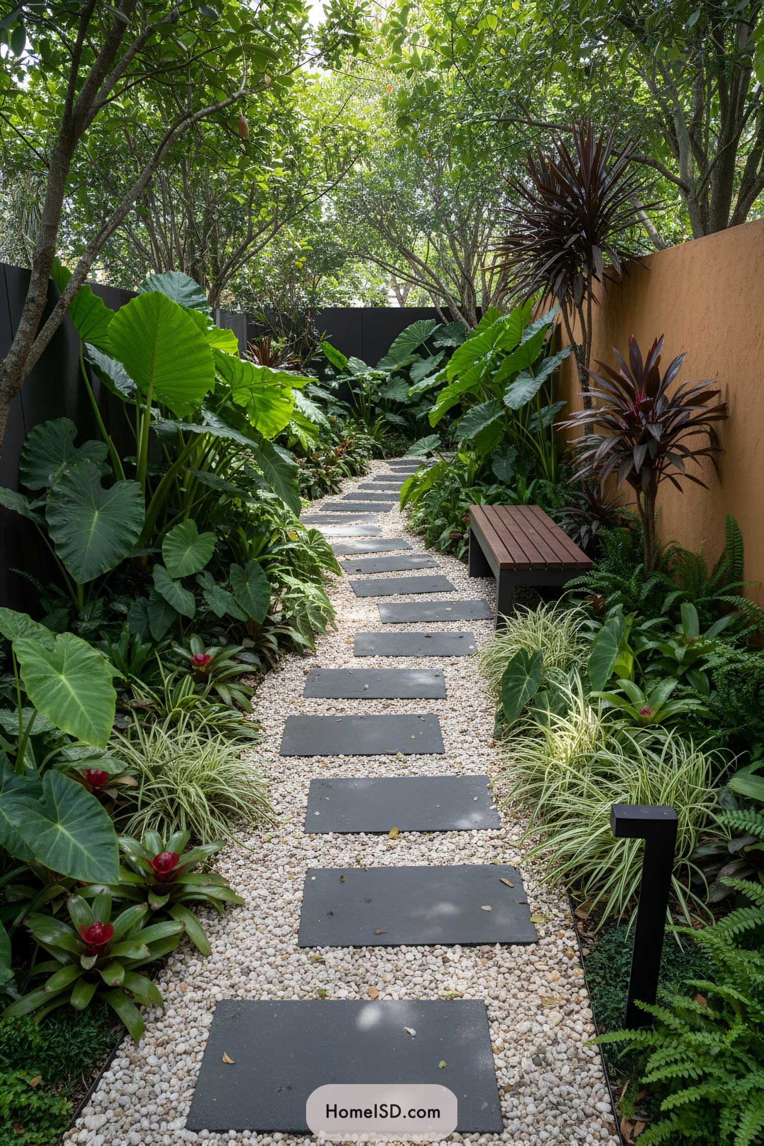 Pebble path with dark stepping stones through lush tropical plants