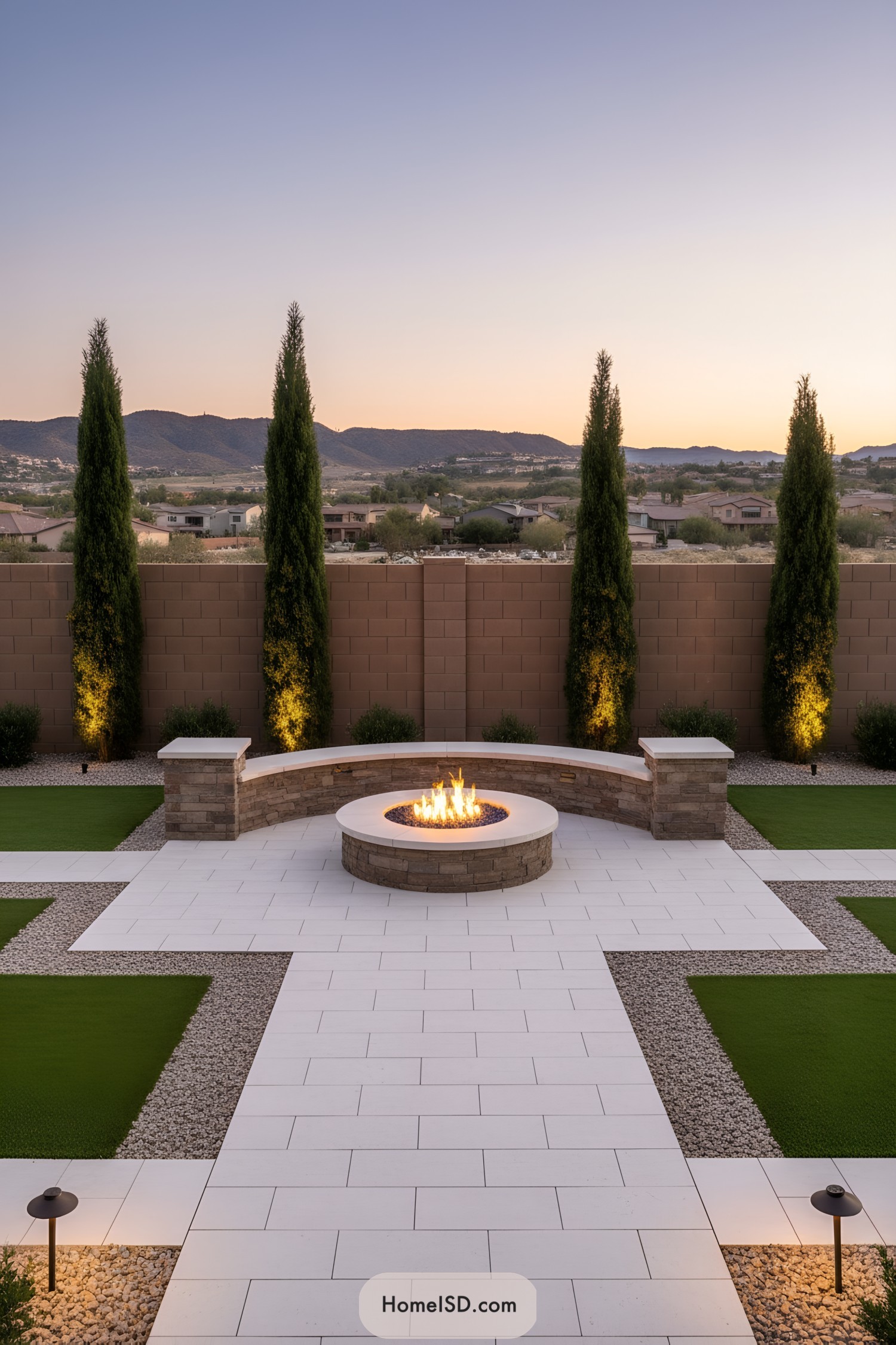 Modern paver patio with circular fire pit and tall evergreens at sunset