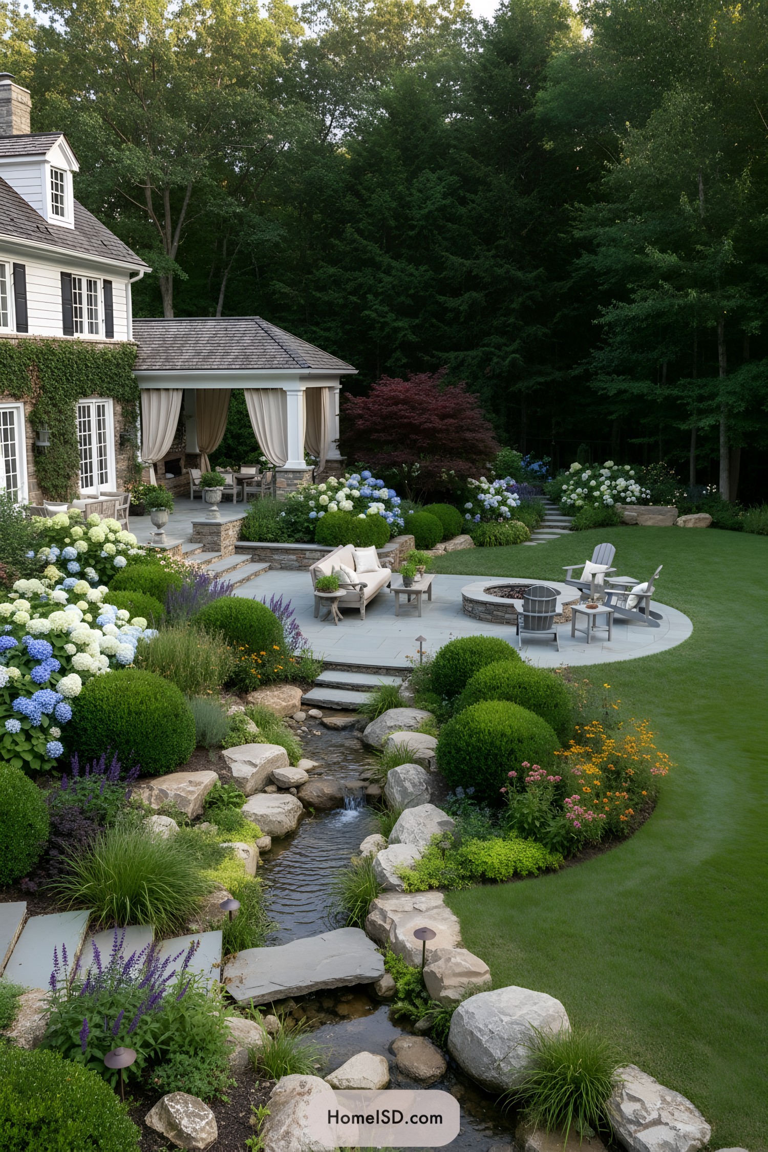 Lush backyard patio with stream, flowers, and circular fire pit