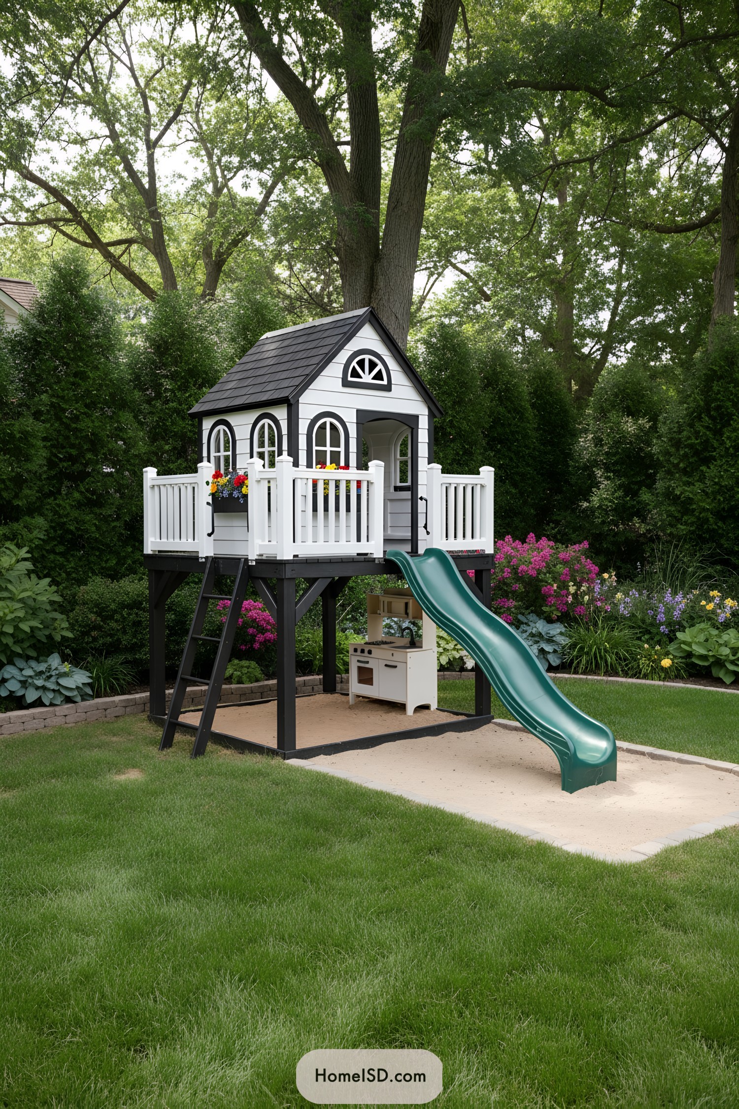 Elevated backyard playhouse with slide over sandbox in lush garden