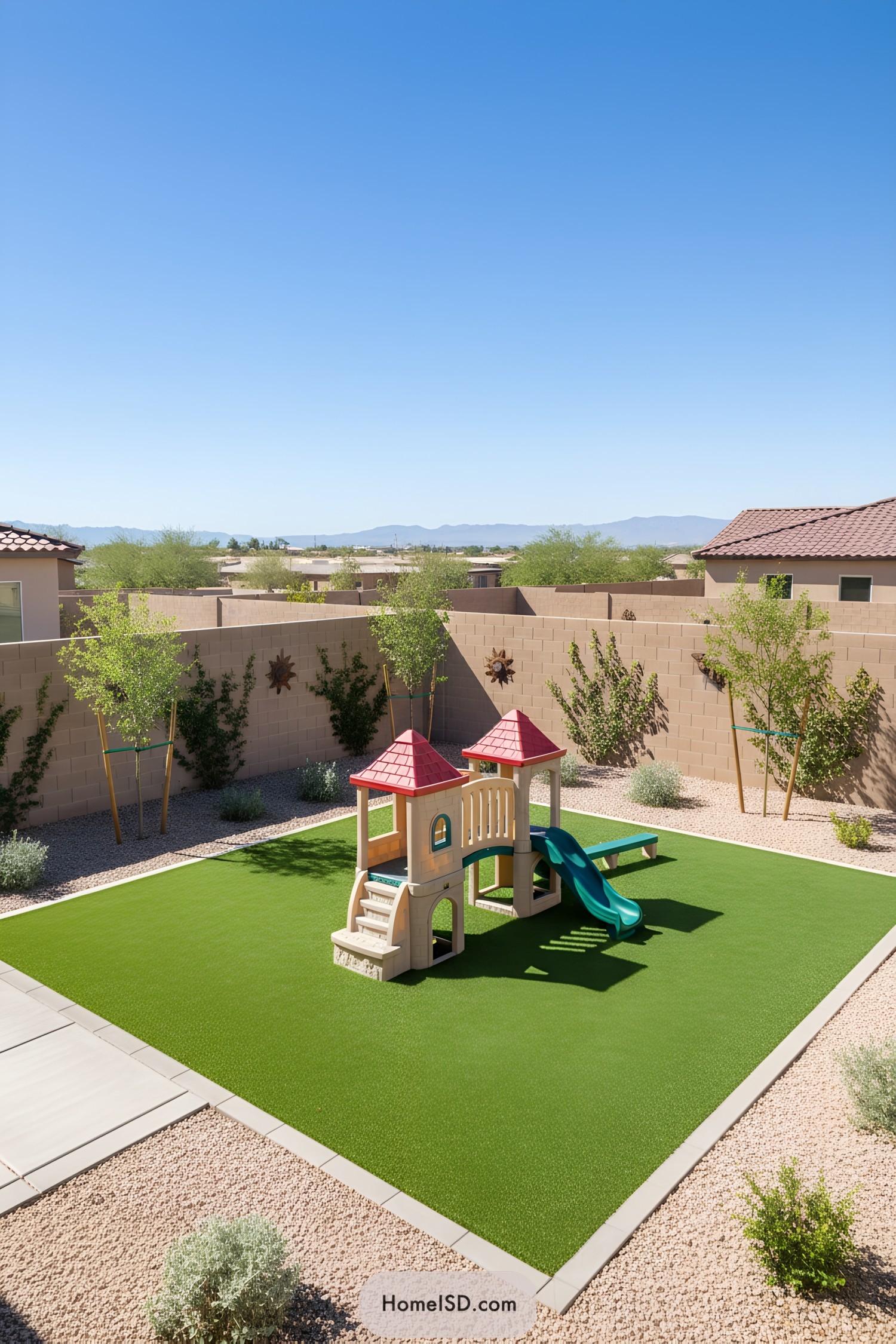 Small plastic playset centered on a square artificial turf lawn in a minimalist desert backyard