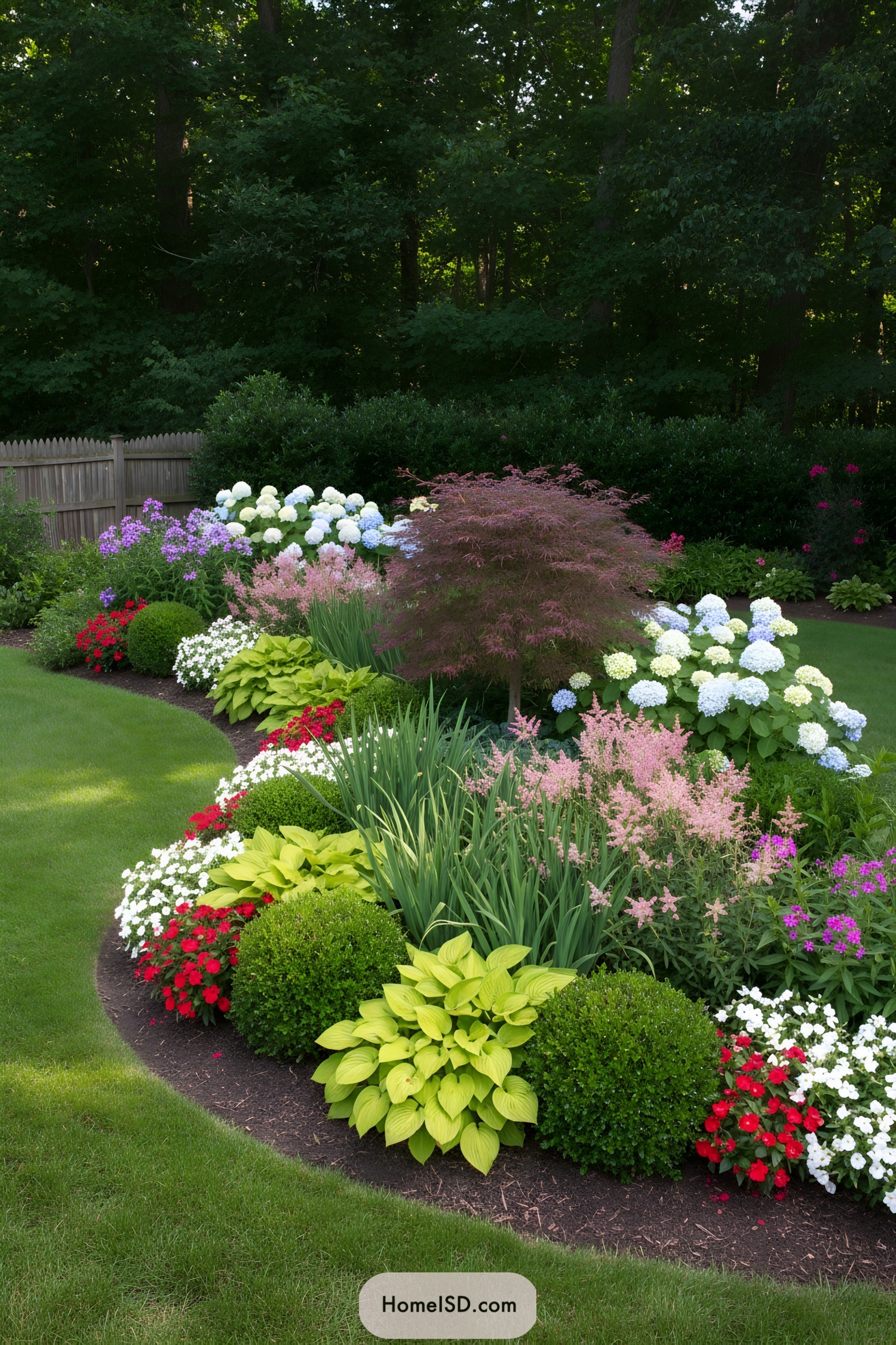 Curved mixed-flower border along a wooded backyard