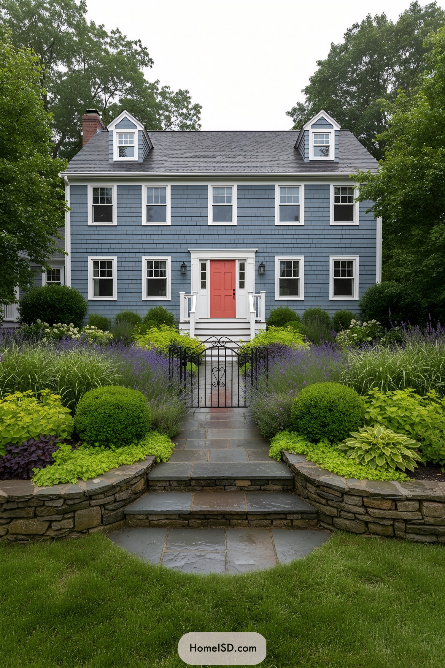 Blue colonial home with layered front garden and slate walkway