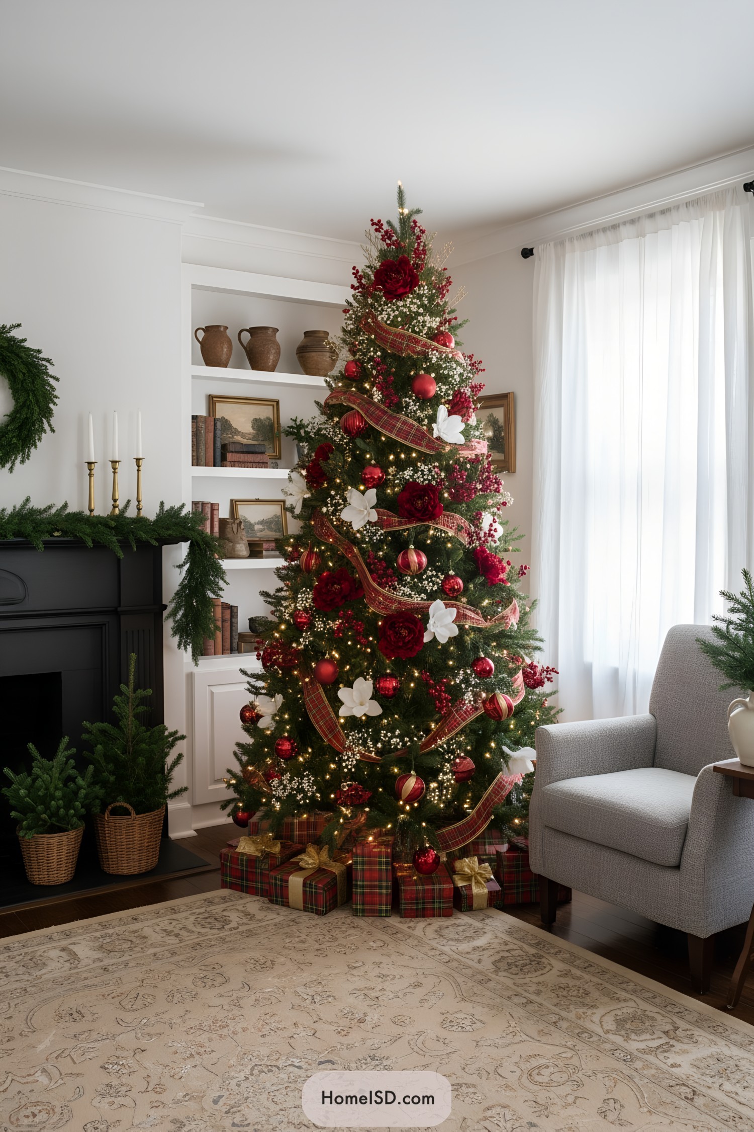 Red-and-gold plaid-ribboned tree with red blooms, white accents, and twinkle lights beside a fireplace