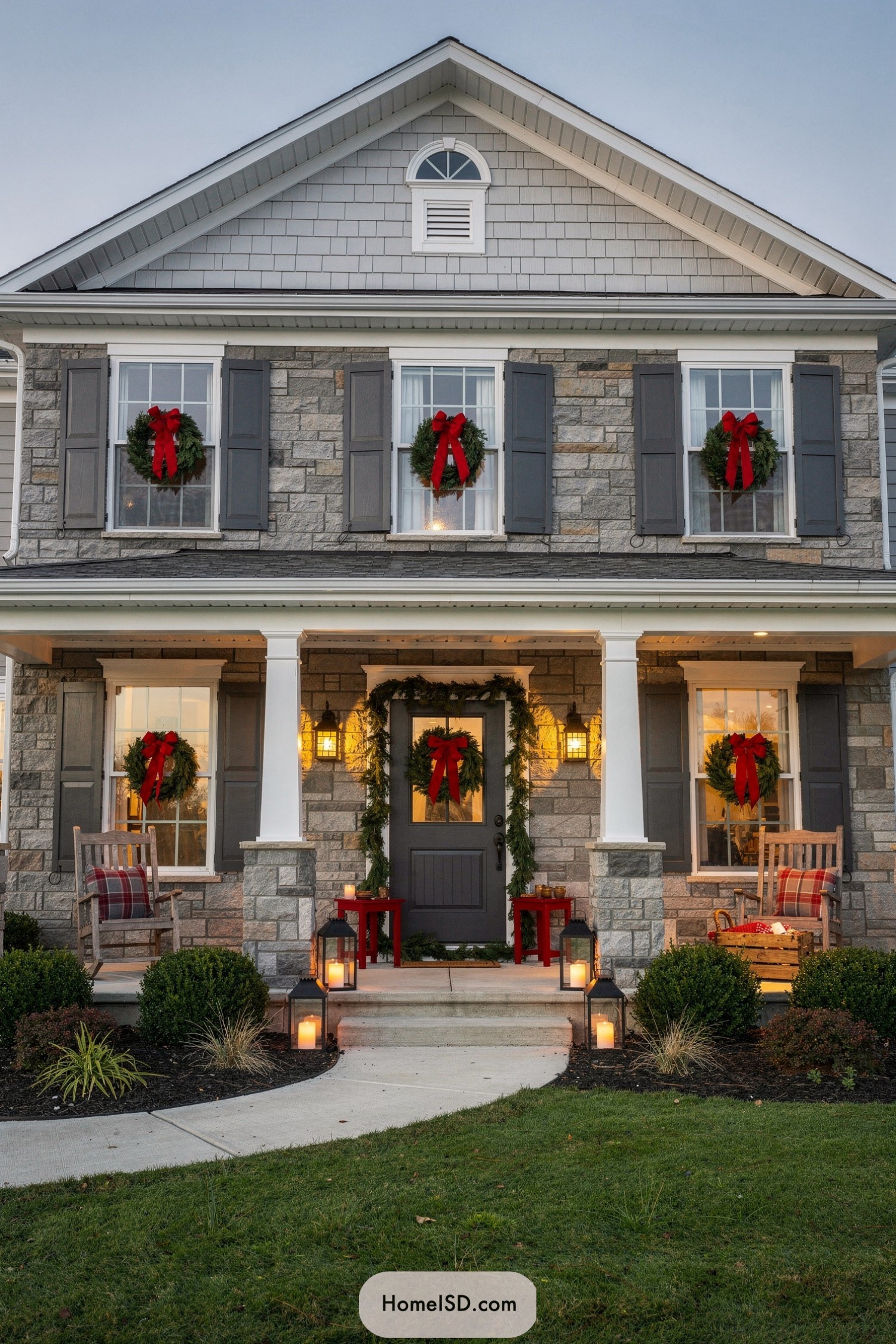 Two story stone house with red-bow wreaths and glowing porch lanterns