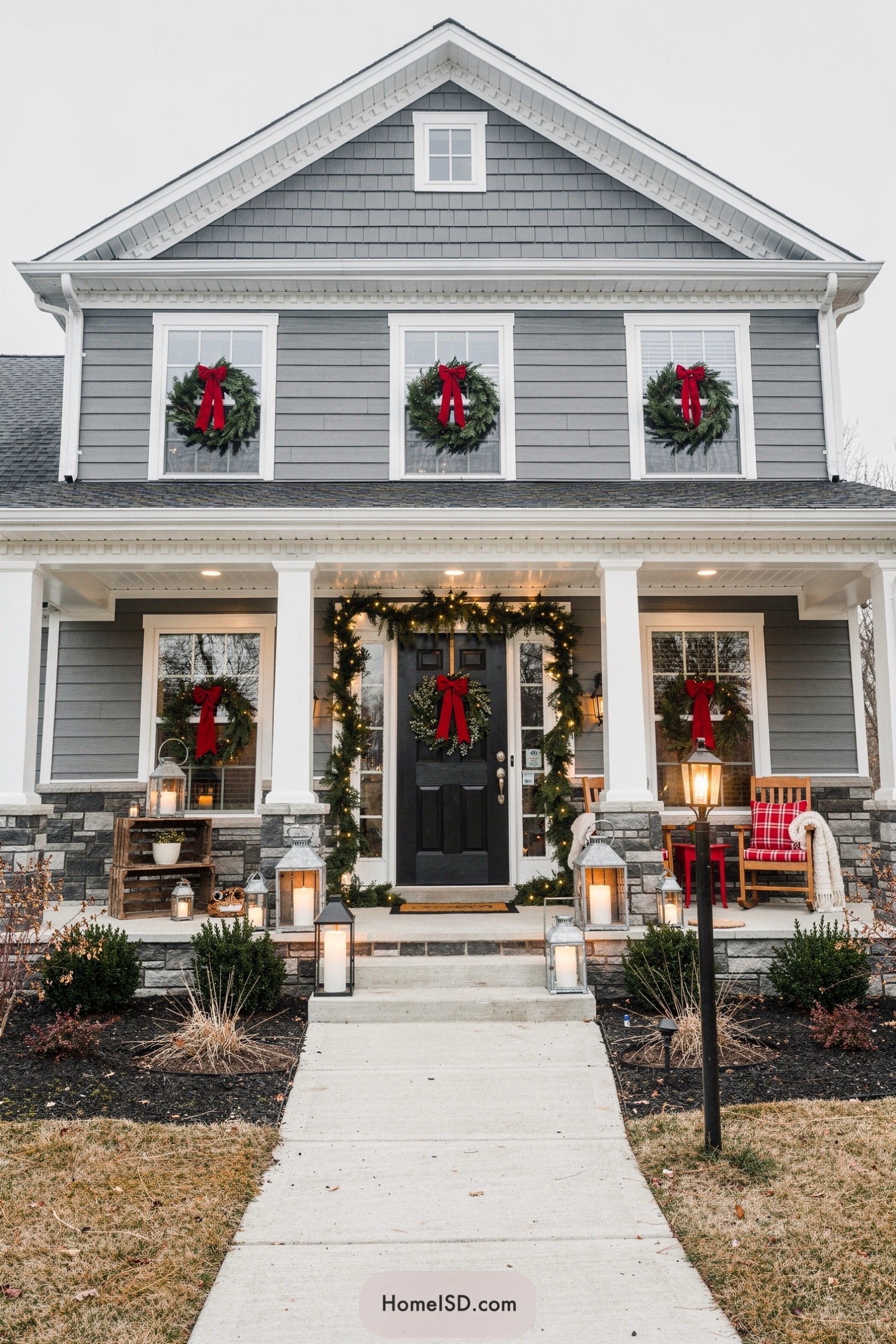 Grey house with matching green wreaths and red bows on every window and around the front door