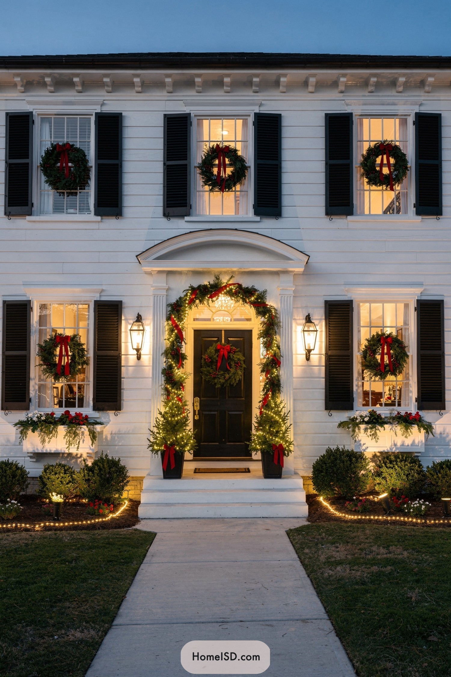 White house with lit Christmas wreaths on windows and doorway