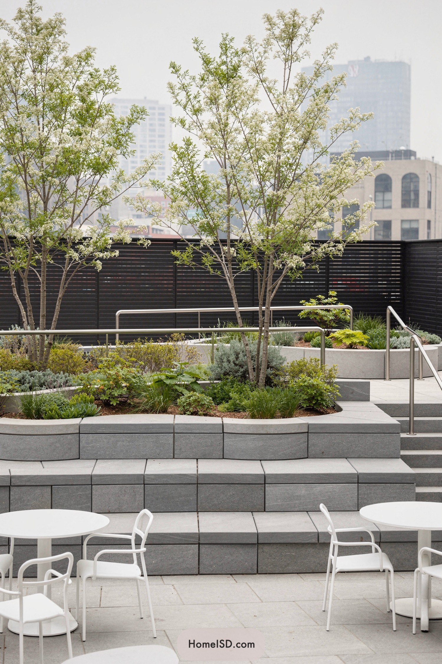 Tiered rooftop garden with stone seating and white café tables