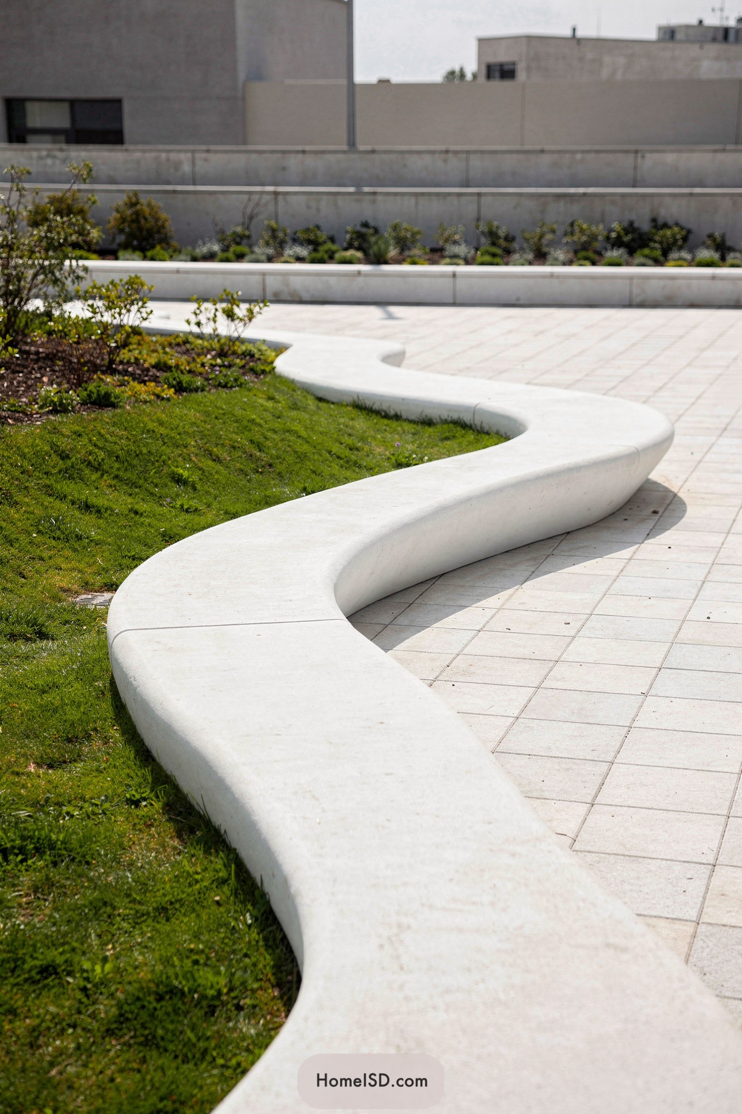 Curved white concrete bench flowing between lawn and paved walkway
