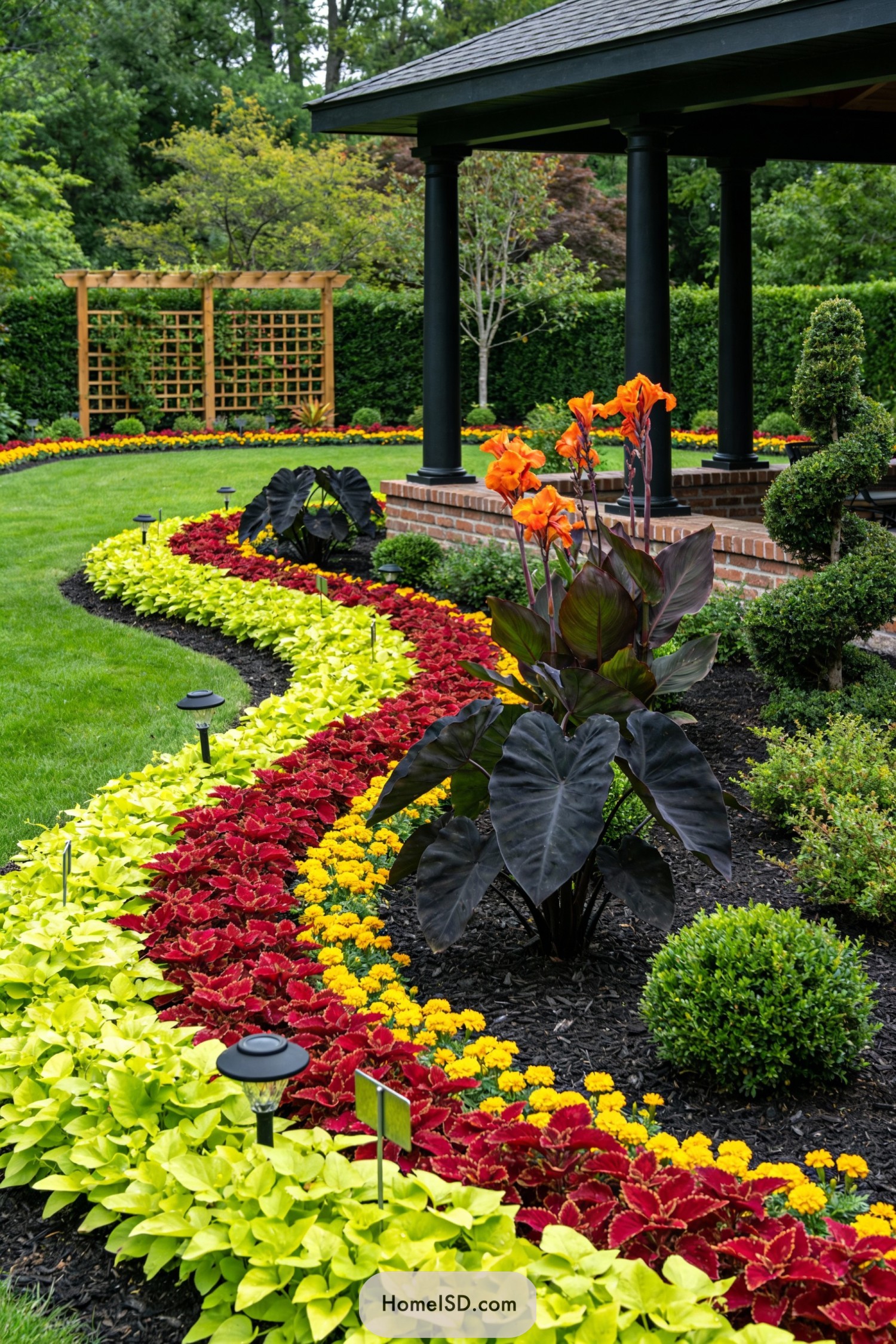 Curving bands of colorful flowers edging a manicured lawn and covered patio