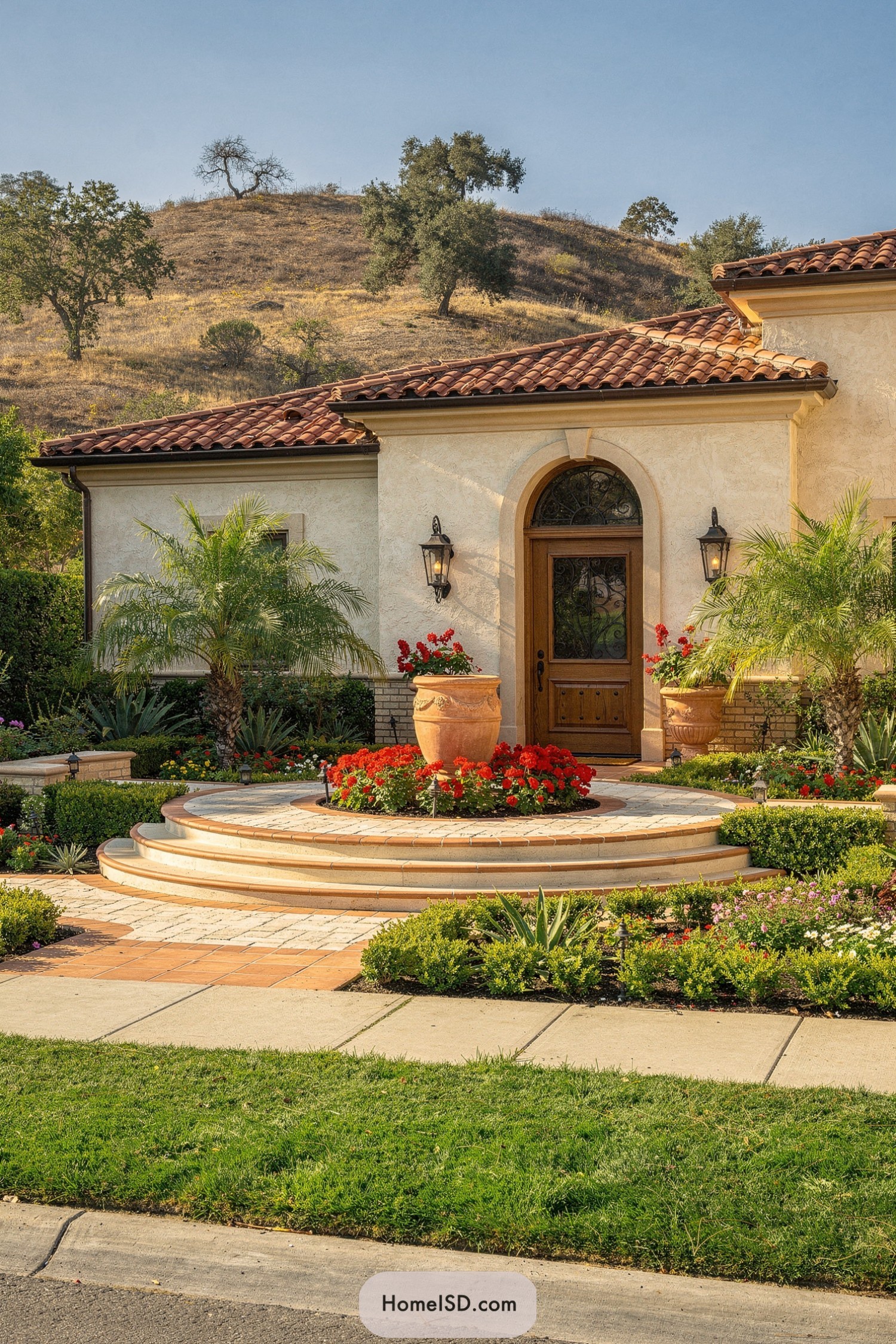 Mediterranean stucco home with tiered circular entry, palms, and red flowers