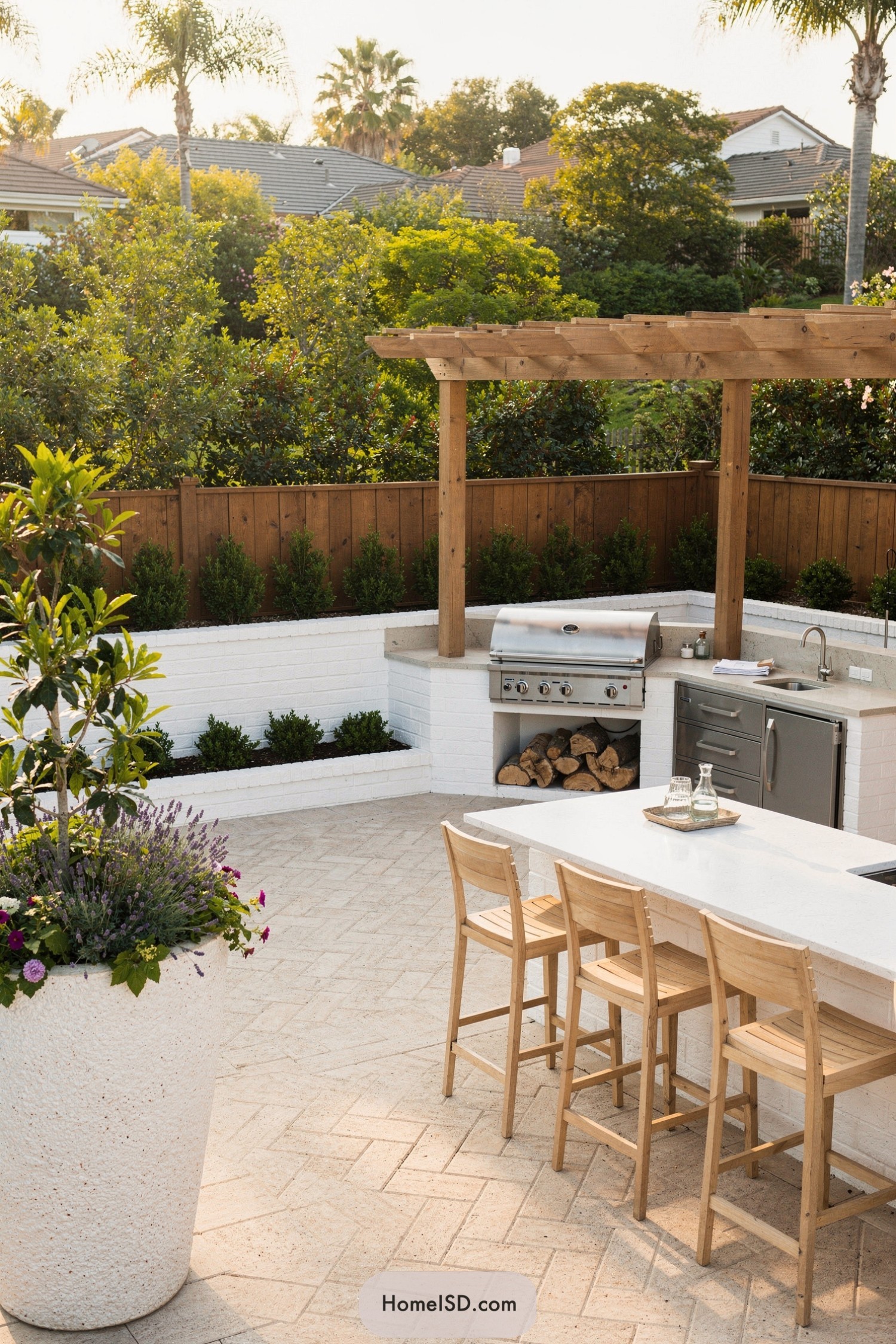 Modern outdoor kitchen with pergola, grill, and bar seating surrounded by lush greenery