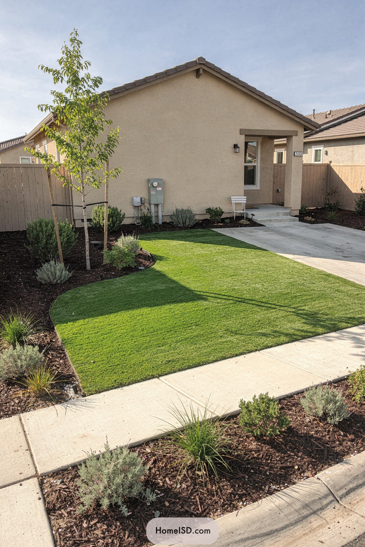 Small front yard with curved turf lawn and mulch planting beds