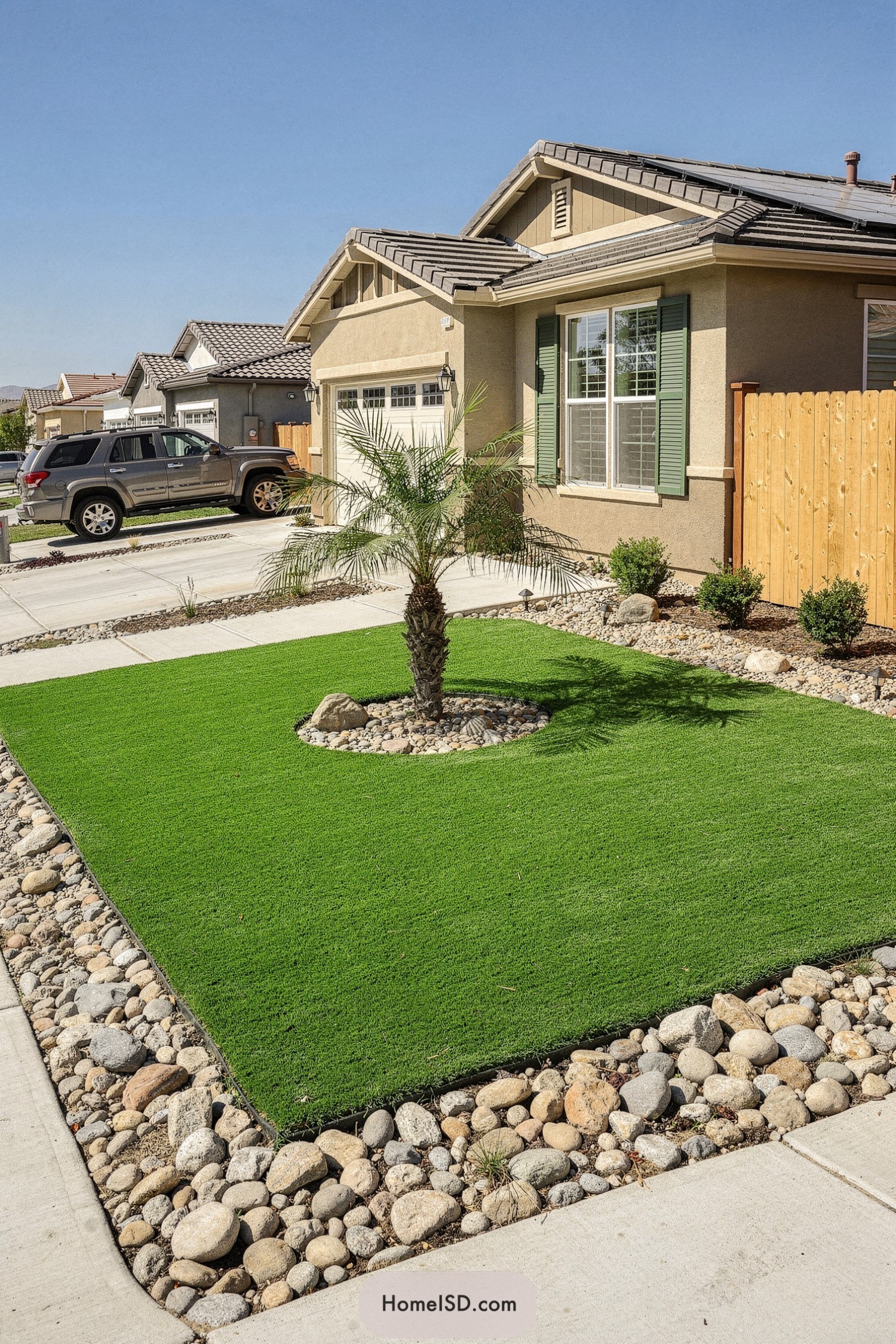 Compact front yard with square turf lawn, single palm tree, and surrounding rock border