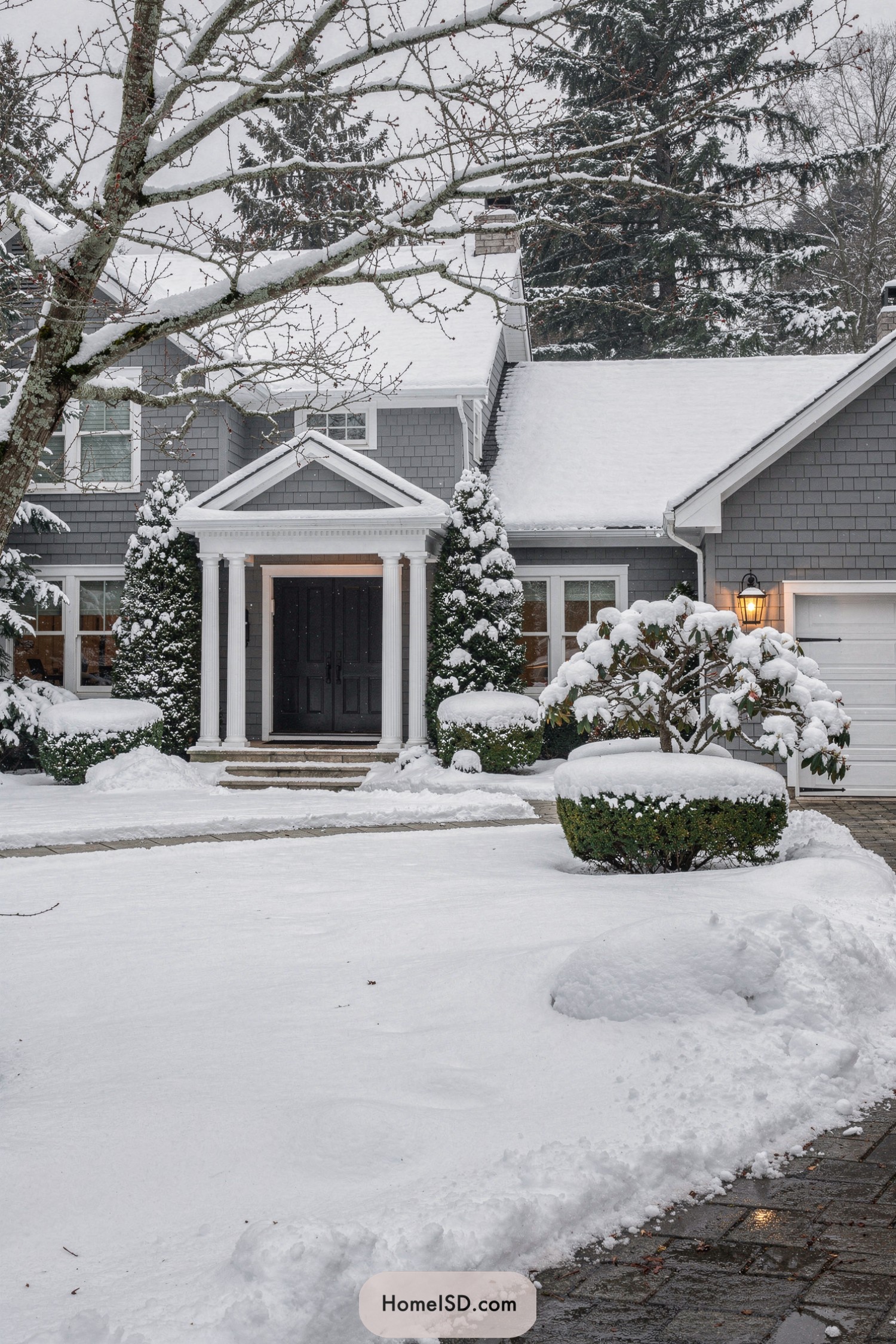 Snow covered gray house with formal entry